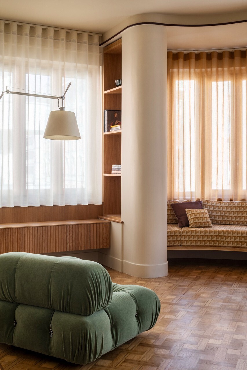 Living room with curved columns framing a timber window seat niche and shelving in soft daylight