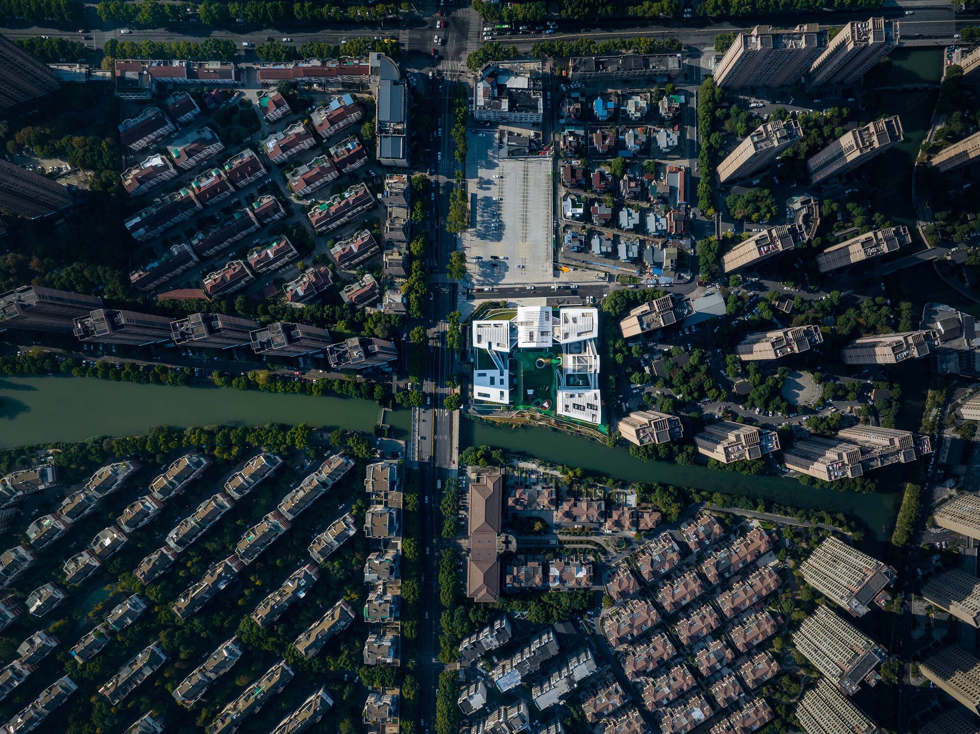 Drone view of the compound surrounded by waterways and tiled-roof residential neighborhoods at midday