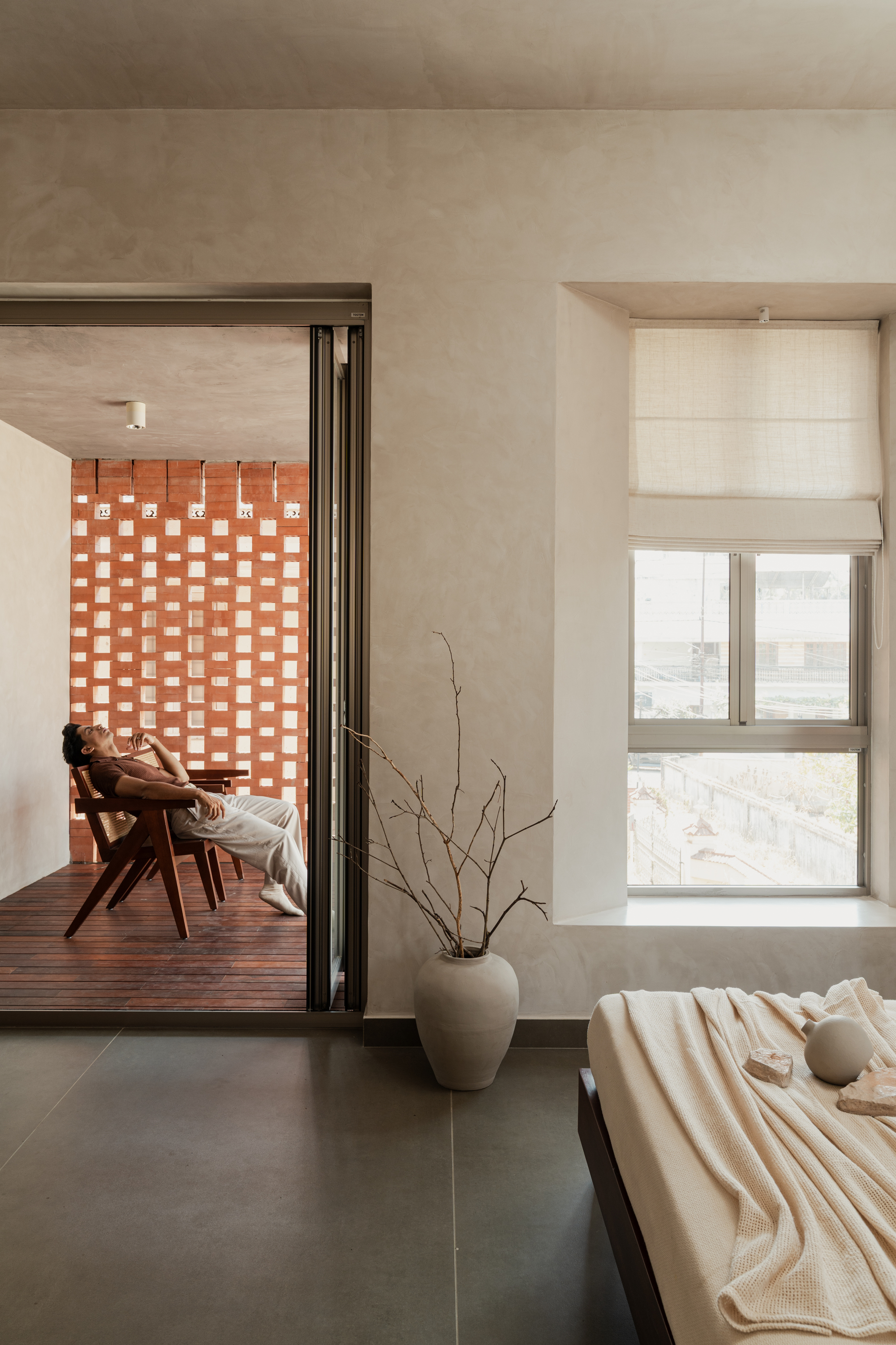 Bedroom with view through folding glass doors to timber deck and perforated brick screen beyond