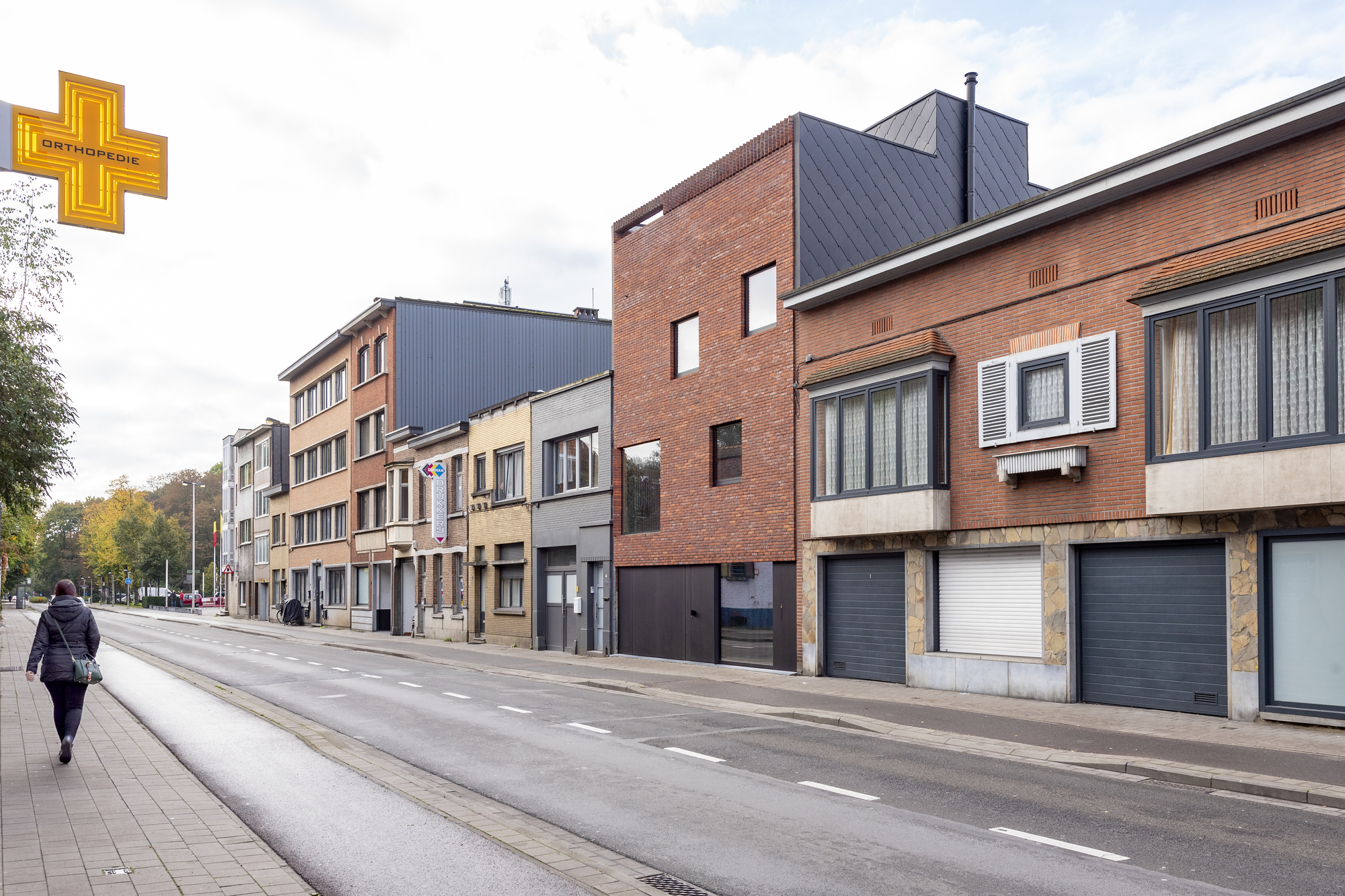 Street view of mixed brick and corrugated metal facades with a pedestrian crossing in autumn