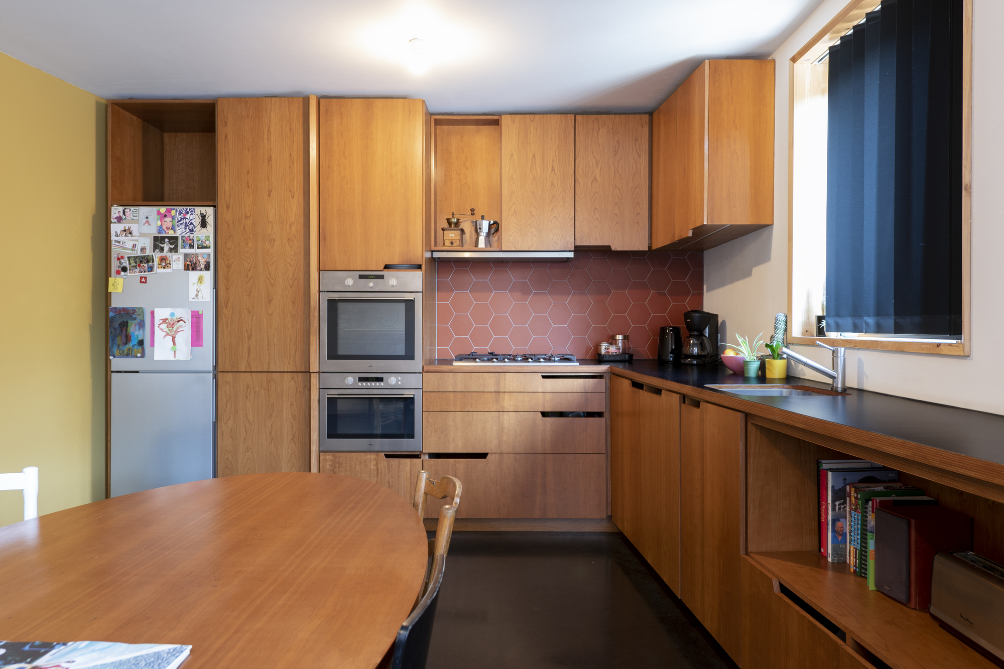 Kitchen with oak cabinetry and a terracotta hexagonal tile backsplash under recessed lighting
