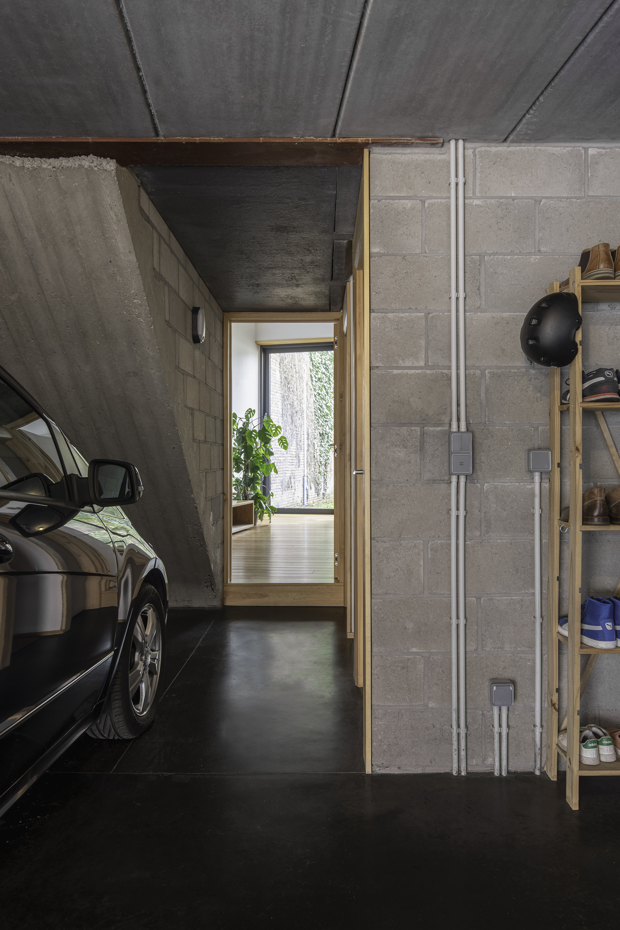 Garage interior with concrete block walls, exposed ceiling and a doorway framing garden greenery