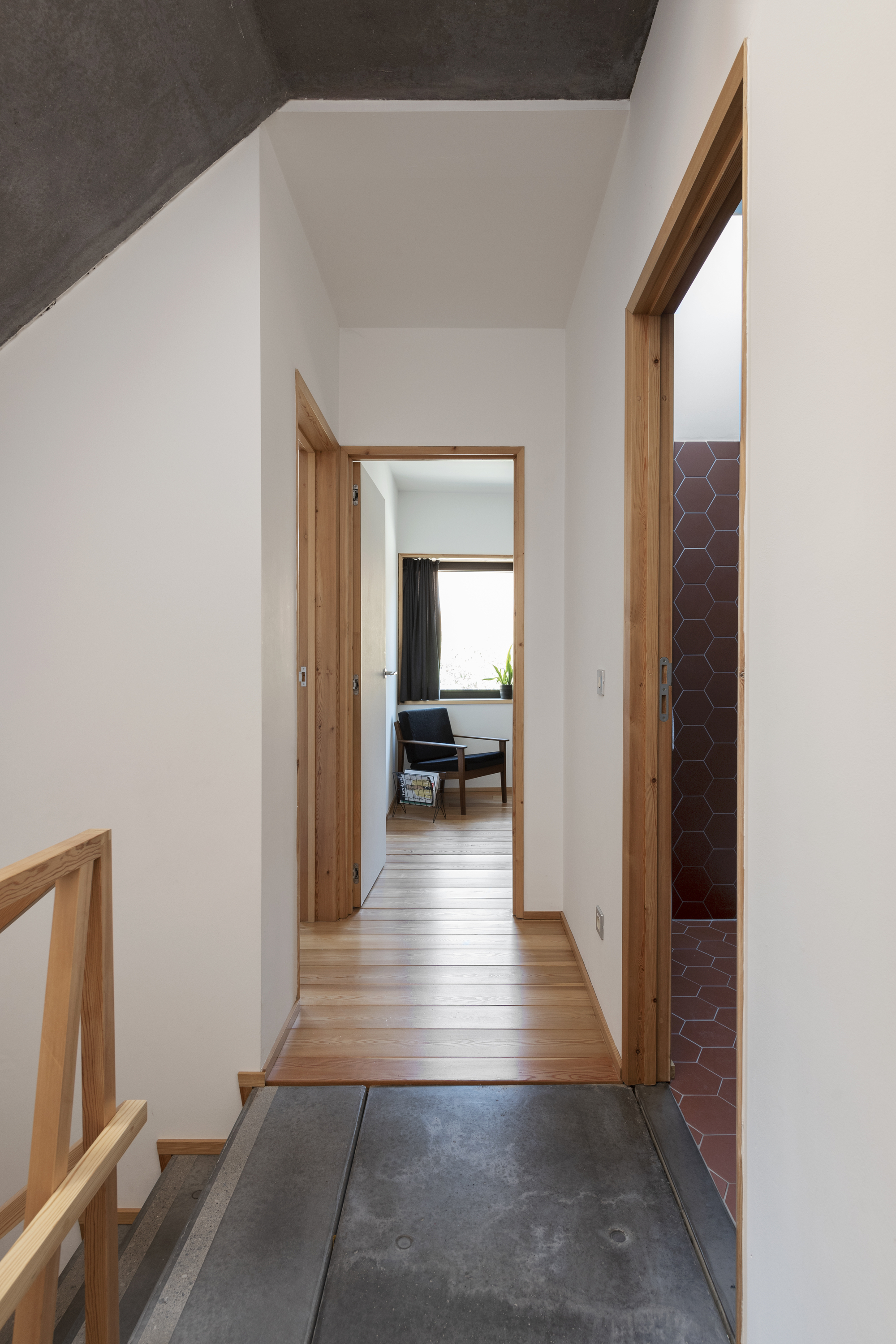 Entry hallway with dark stone flooring transitioning to timber, white walls and timber-framed doorways
