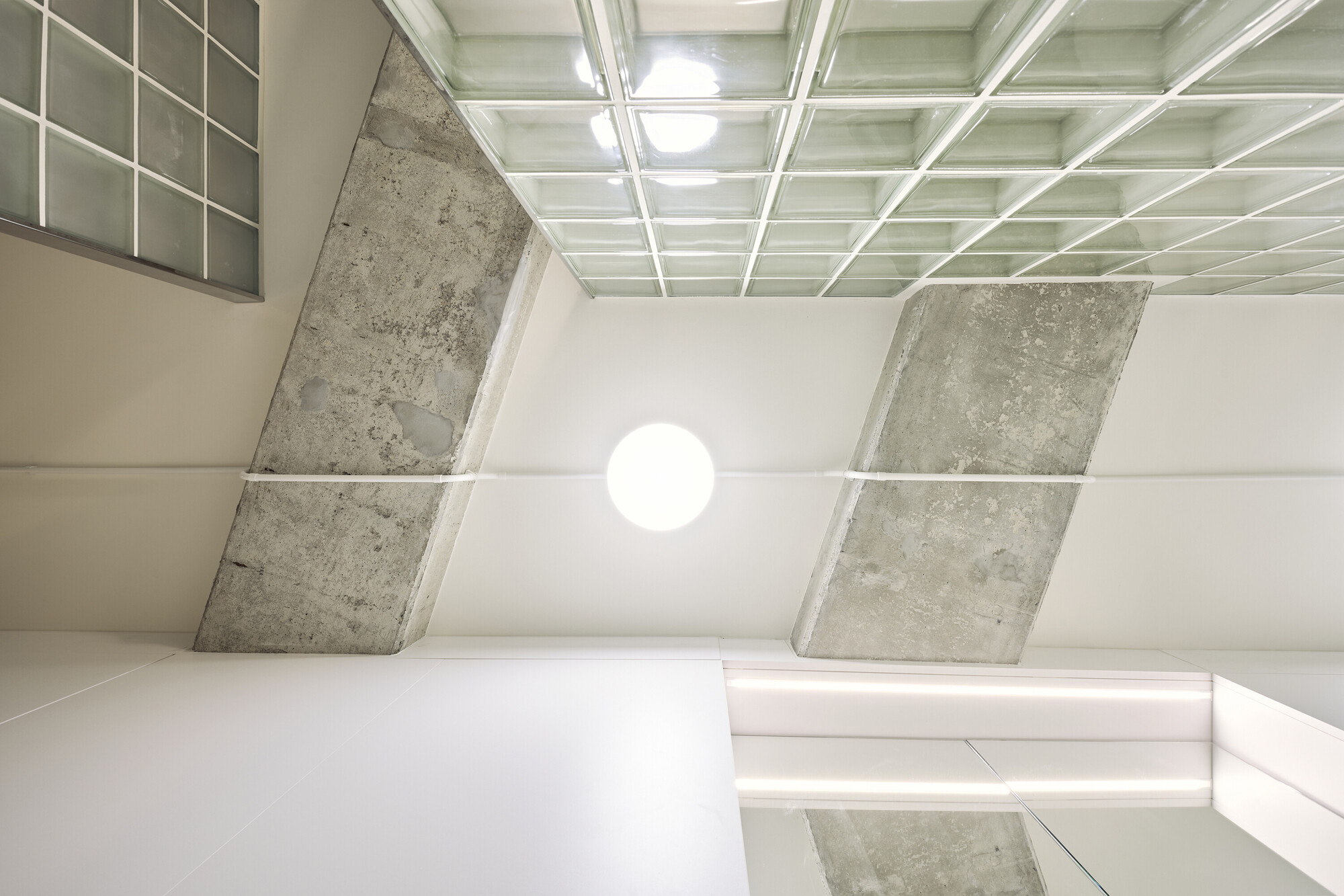 Upward view of coffered ceiling with angled concrete beams meeting at a central globe light