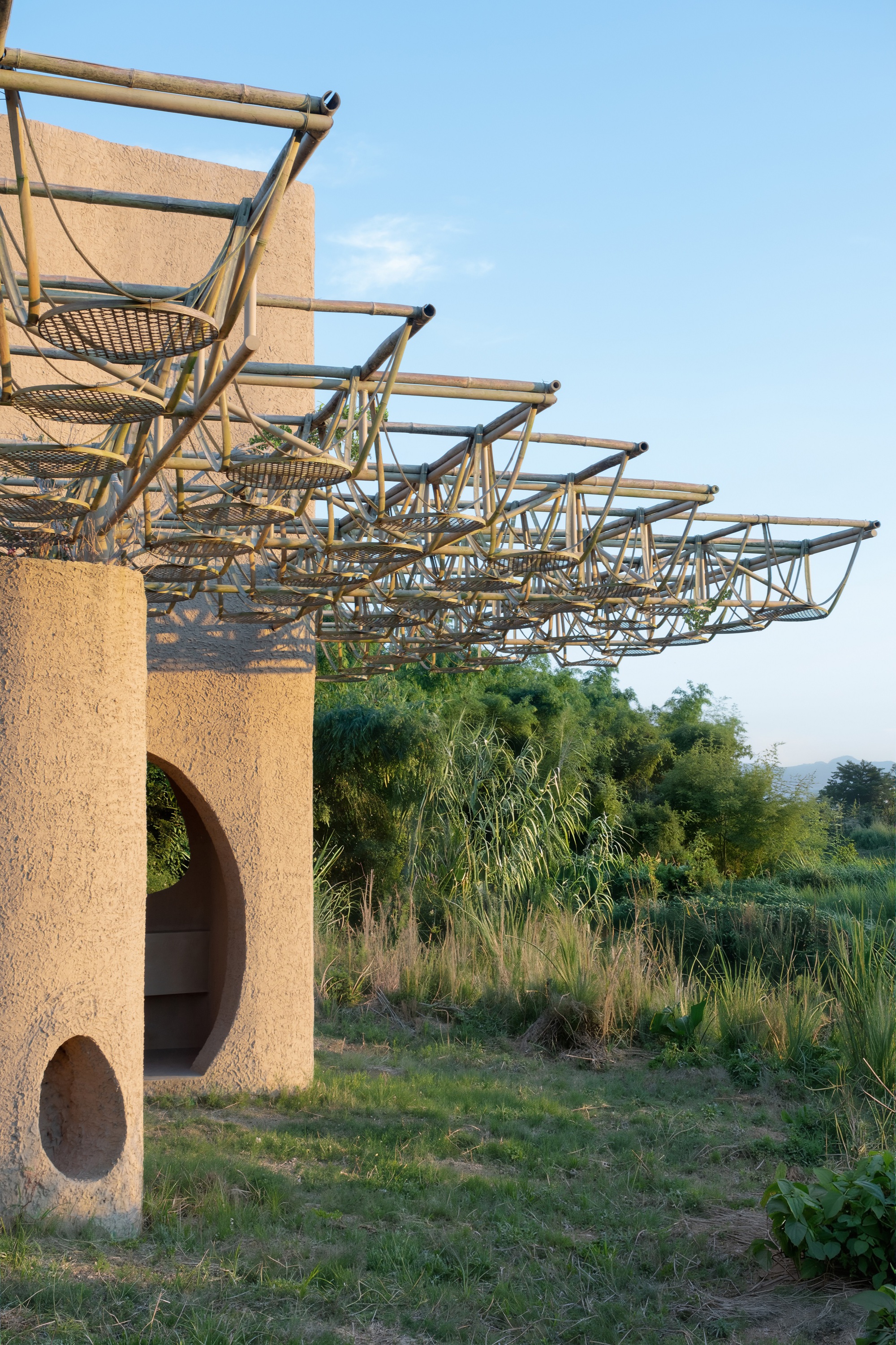 Detail of the bamboo frame canopy structure extending from cylindrical earthen columns with arched voids
