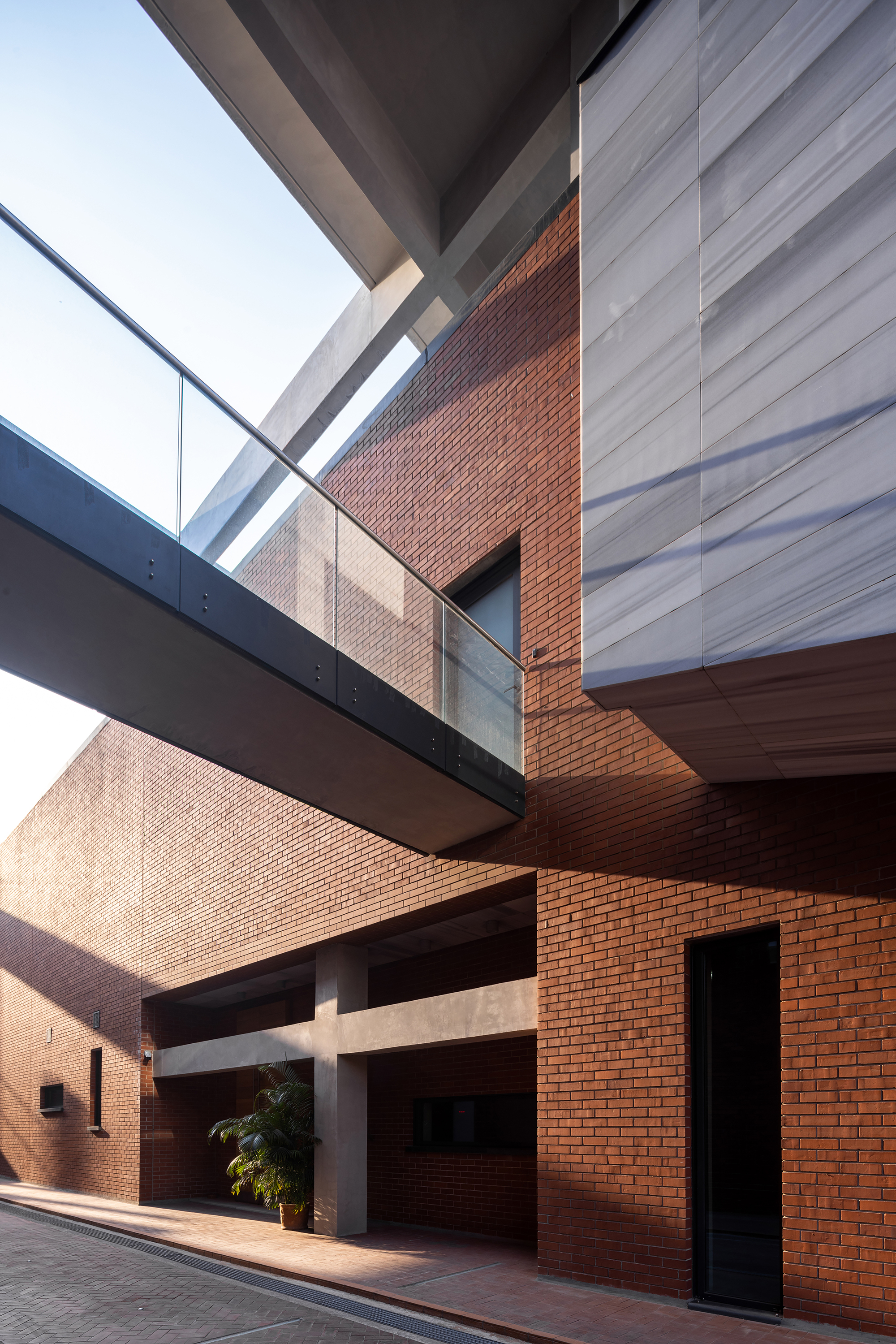Interior courtyard with red brick walls crossed by horizontal concrete bridges and glazed openings above