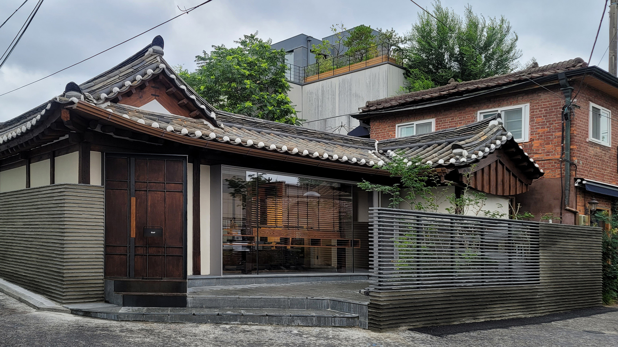Street view of the entry facade with horizontal ribbed metal cladding and curved tile roof