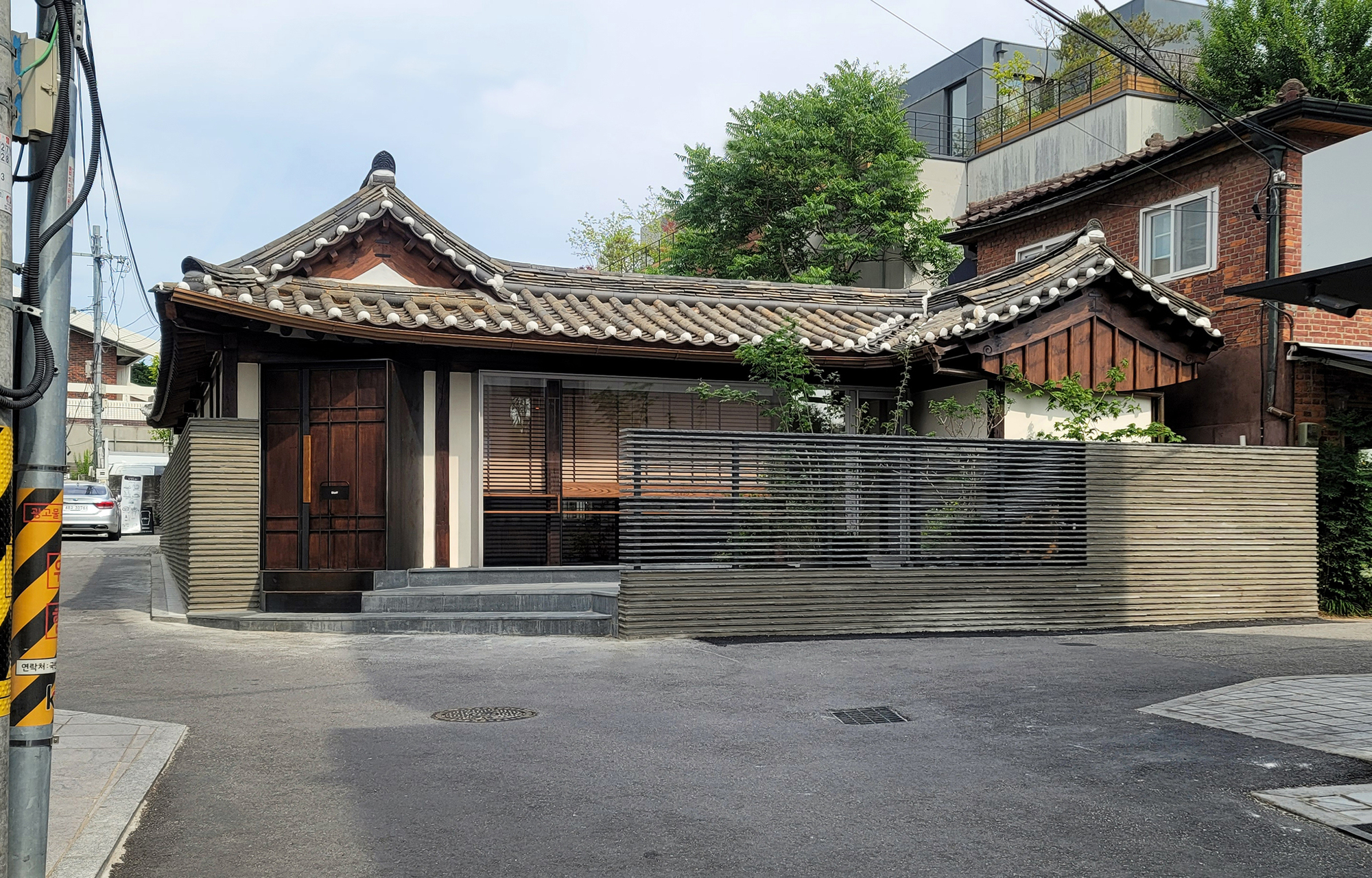 Corner view showing the ribbed metal perimeter wall and curved tile roofline from the street