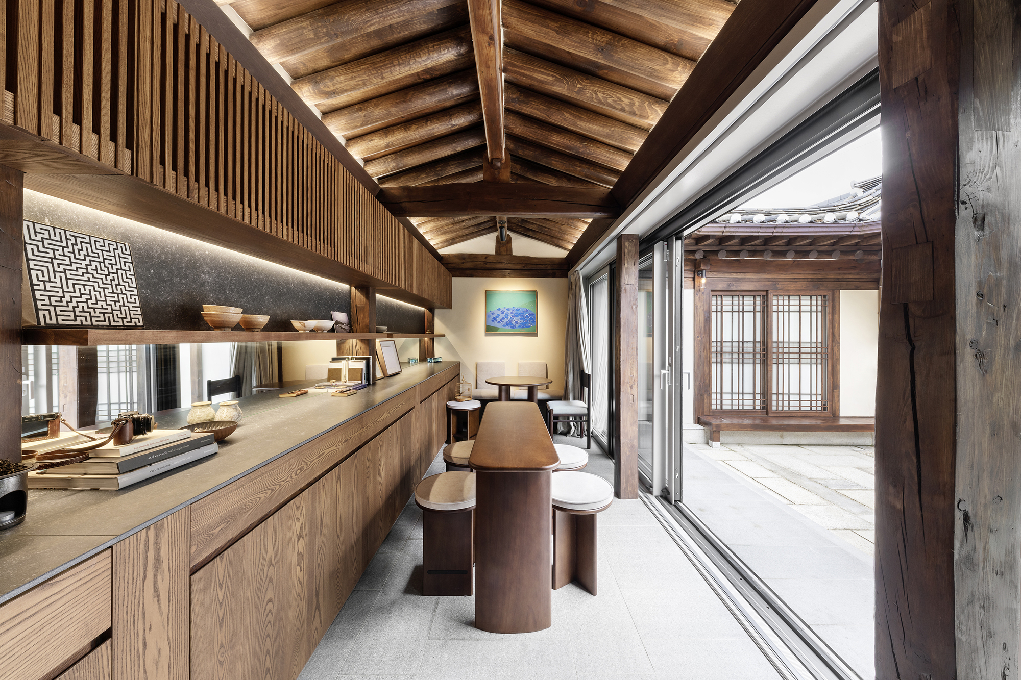 Interior kitchen with exposed timber rafters, vertical wood slat partitions and backlit countertop alcove