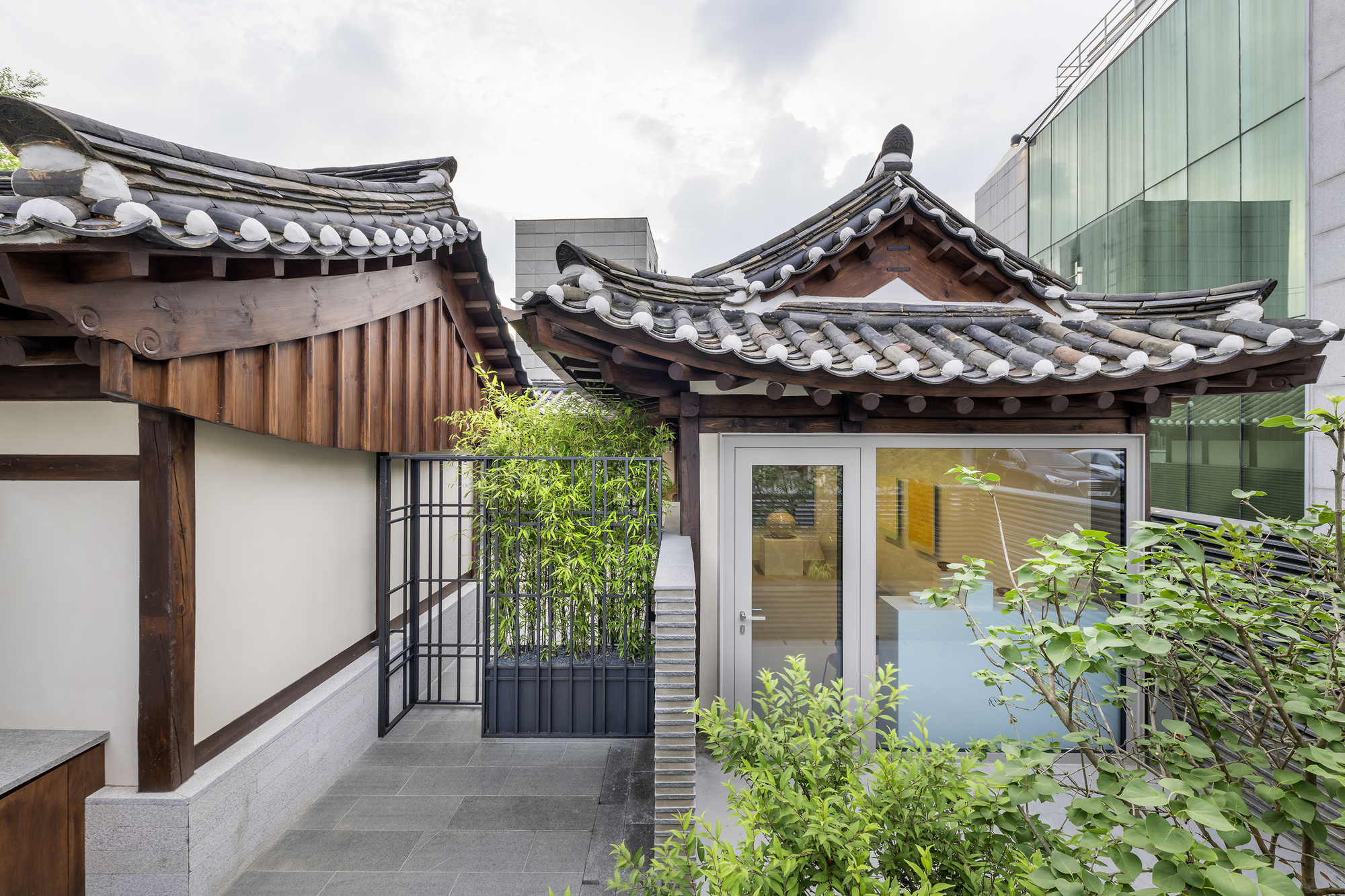 Rooftop terrace showing curved tile eaves, planted bamboo beds and ribbed metal partition wall