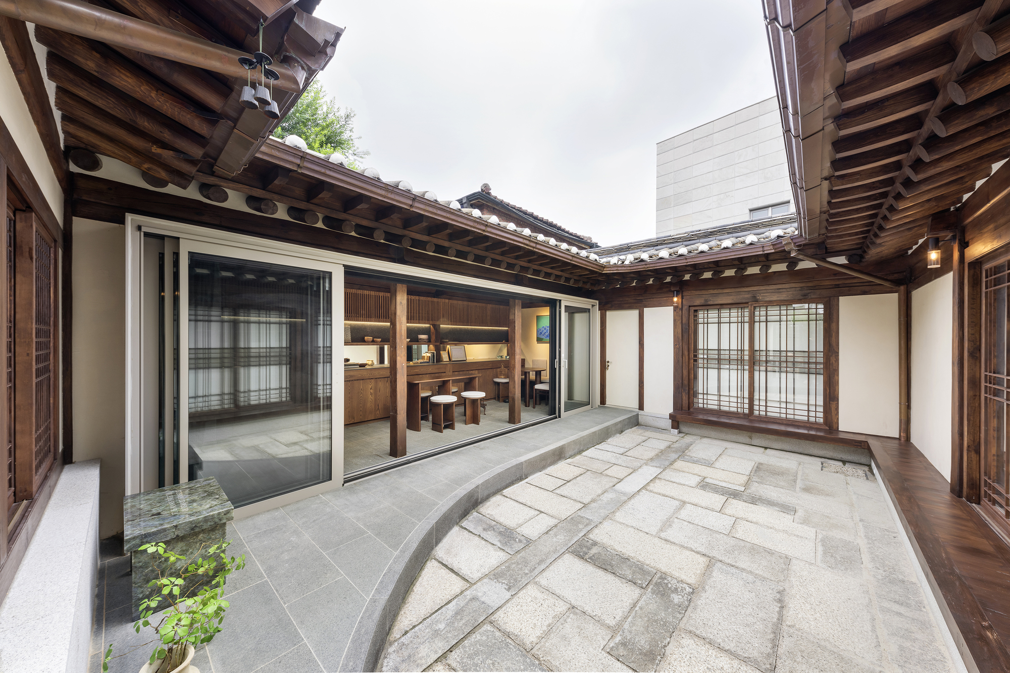 Courtyard with stone paving and planted bed surrounded by traditional timber-framed buildings under overcast sky