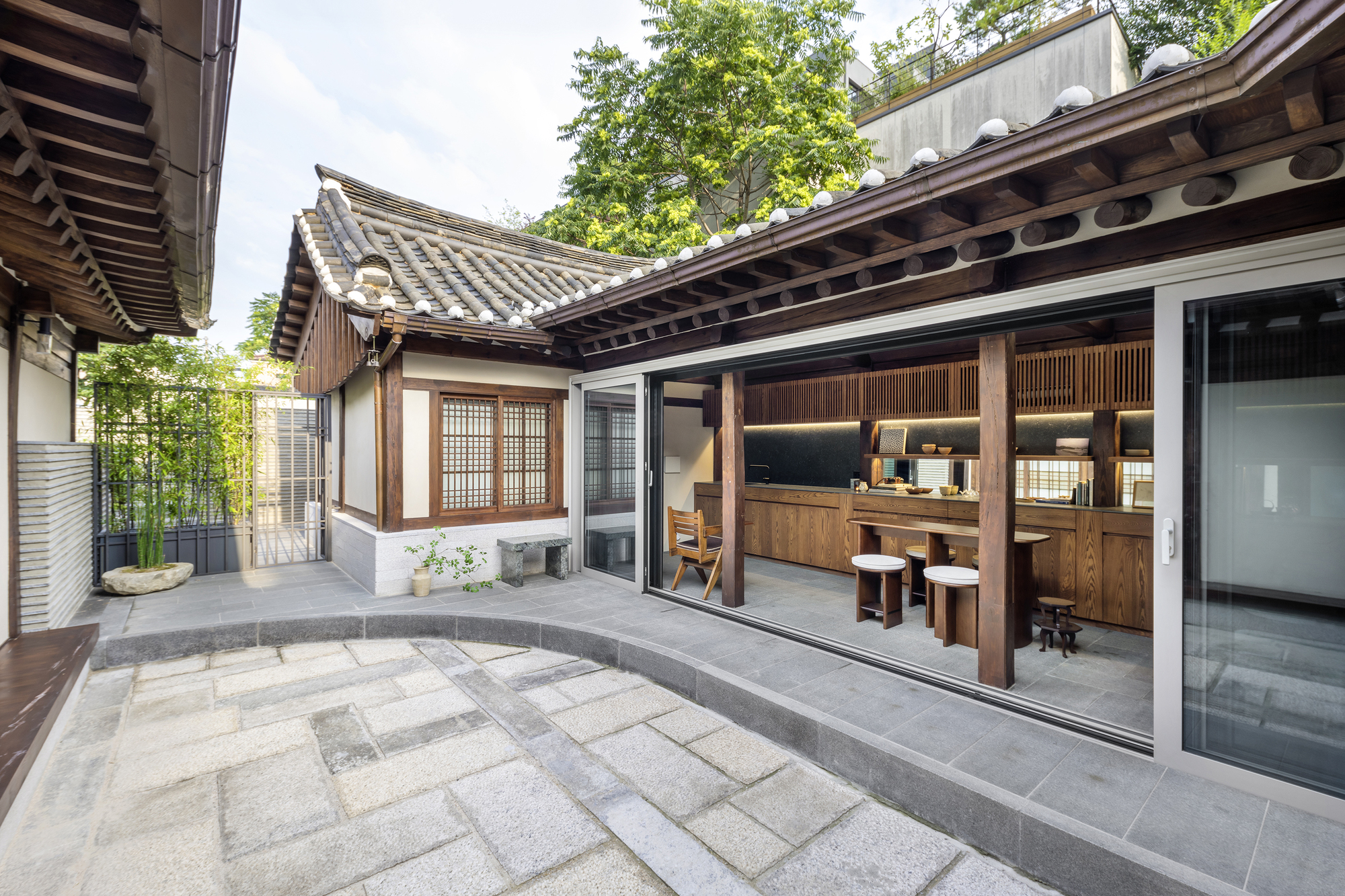 Courtyard view with grey stone pavers linking traditional tiled-roof structures to glazed interior spaces