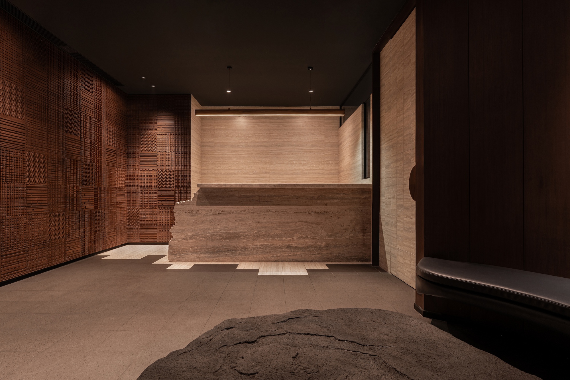 Travertine desk facing woven timber screen wall with geometric patterns in warm interior lighting