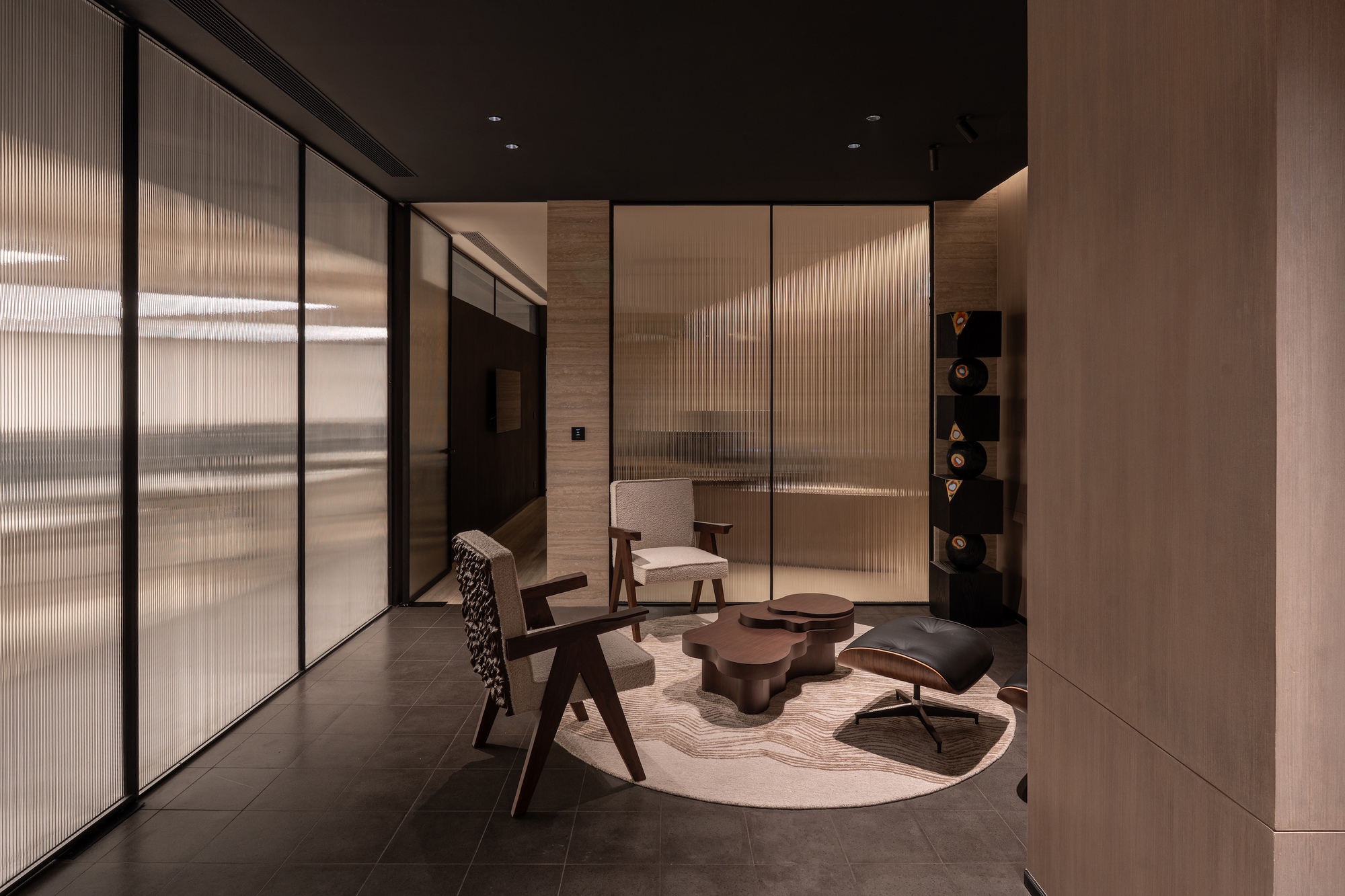 Glass-partitioned meeting room with fluted panels and wooden furniture on a circular rug