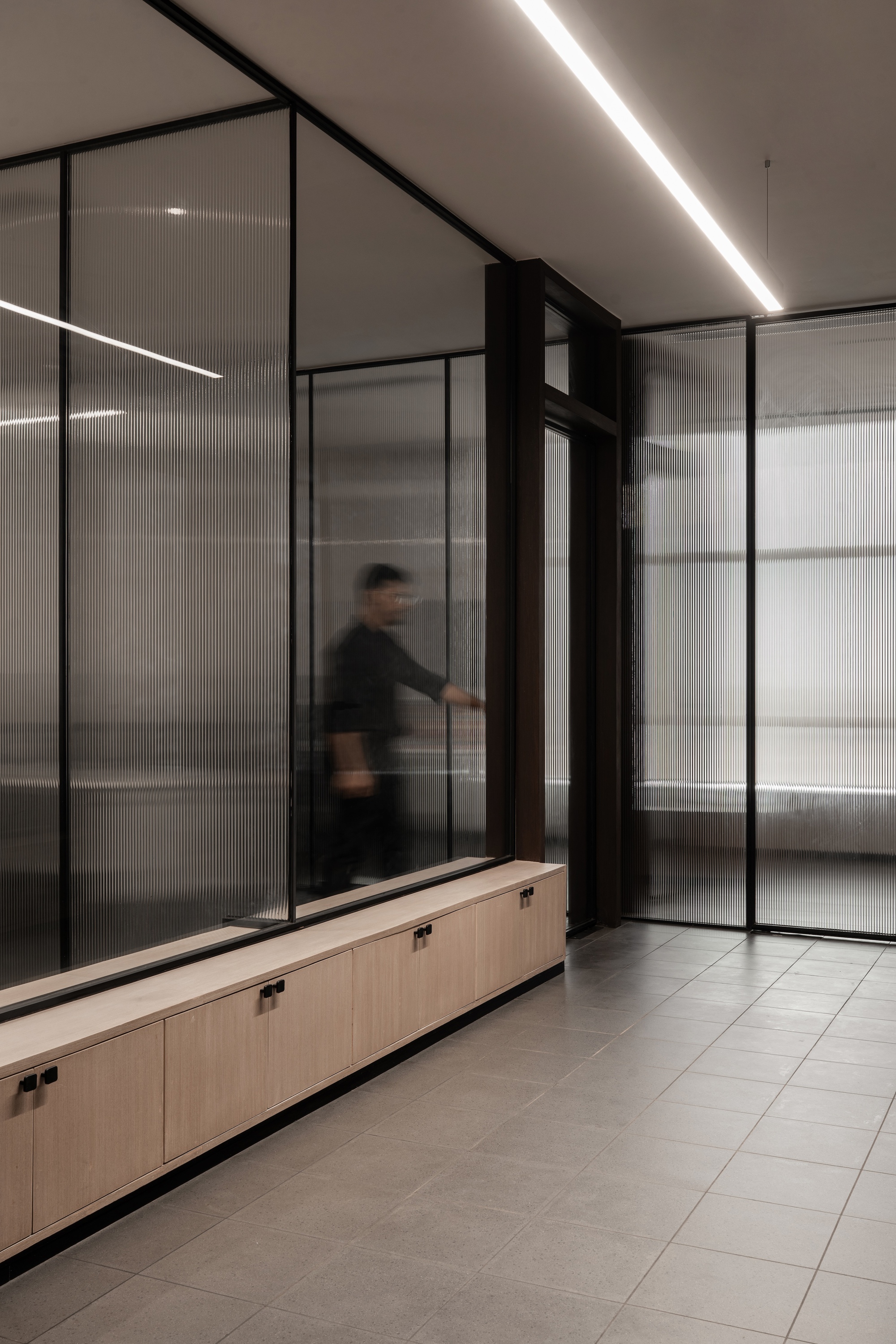Corridor with translucent glass partitions and a person in motion captured with blur