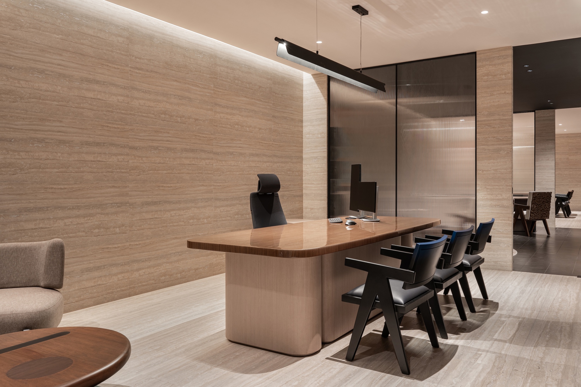 Meeting area with timber table, black chairs, and textured wood wall with concealed linear lighting