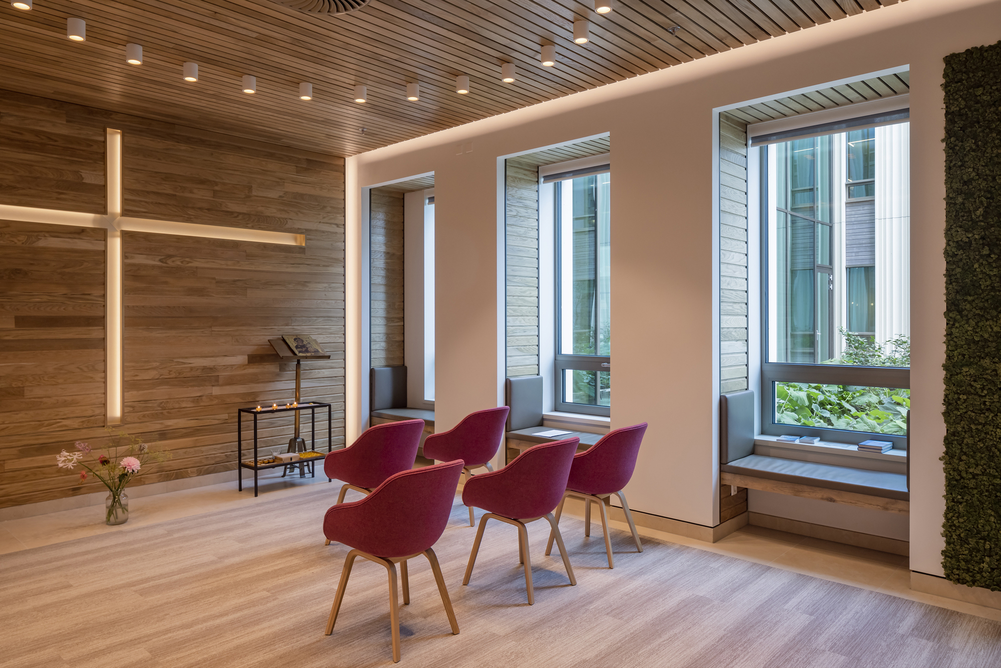 Chapel space with timber slat ceiling, wooden cross, and red upholstered chairs