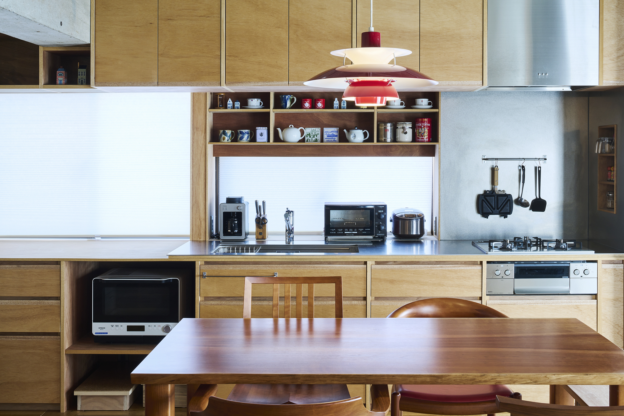 Kitchen with light oak cabinetry, open shelving, and a red pendant light above the workspace