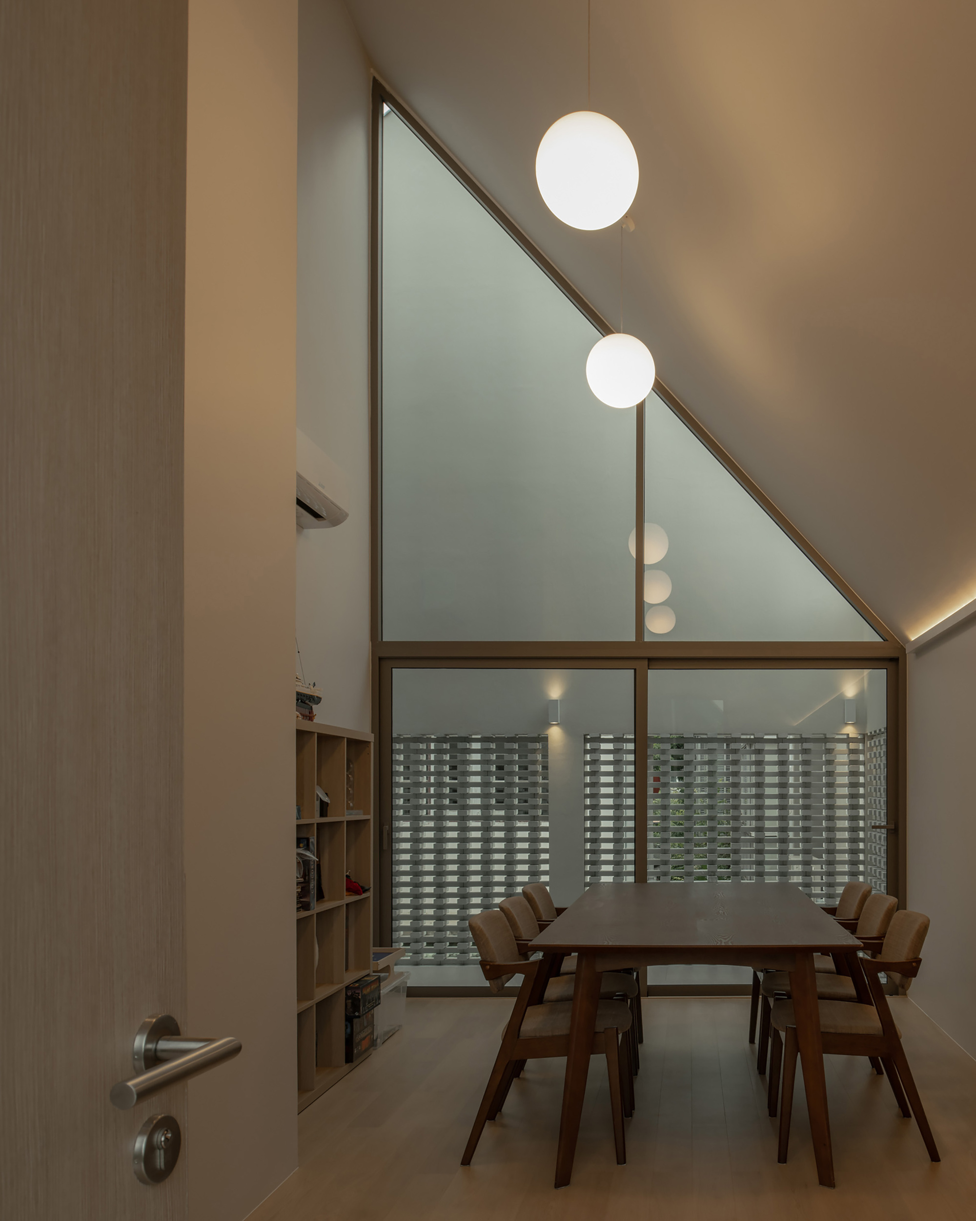 Dining room with angled ceiling featuring frosted glass gable window and spherical pendant lights at dusk