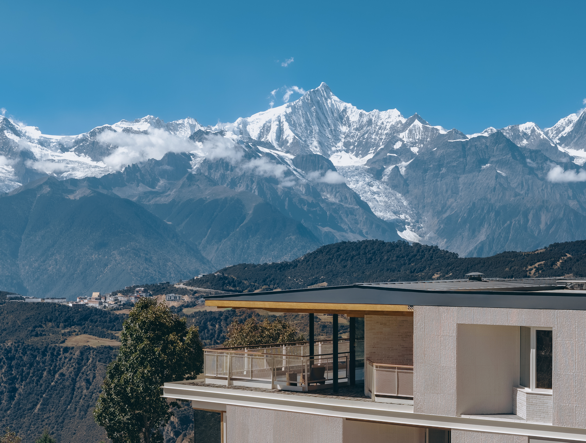 Rooftop terrace with timber canopy and glass railings against a backdrop of snow-capped mountain peaks
