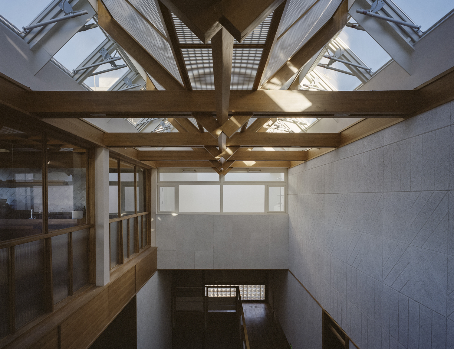 Interior view of timber roof trusses with skylights above a stairwell and tiled wall panels