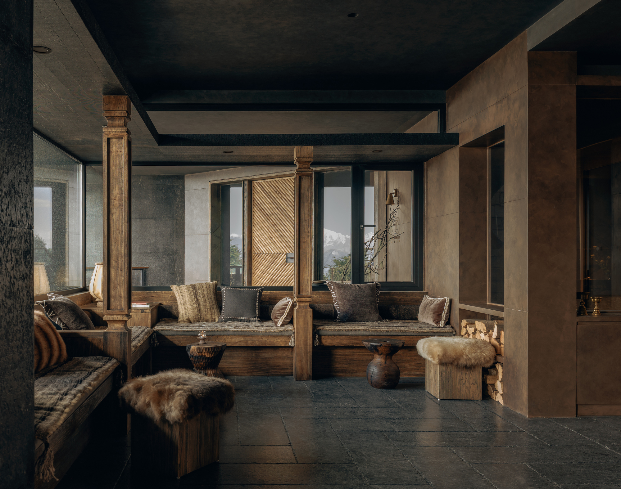 Lounge space with carved wooden columns, dark ceiling beams, and mountain views through tall windows