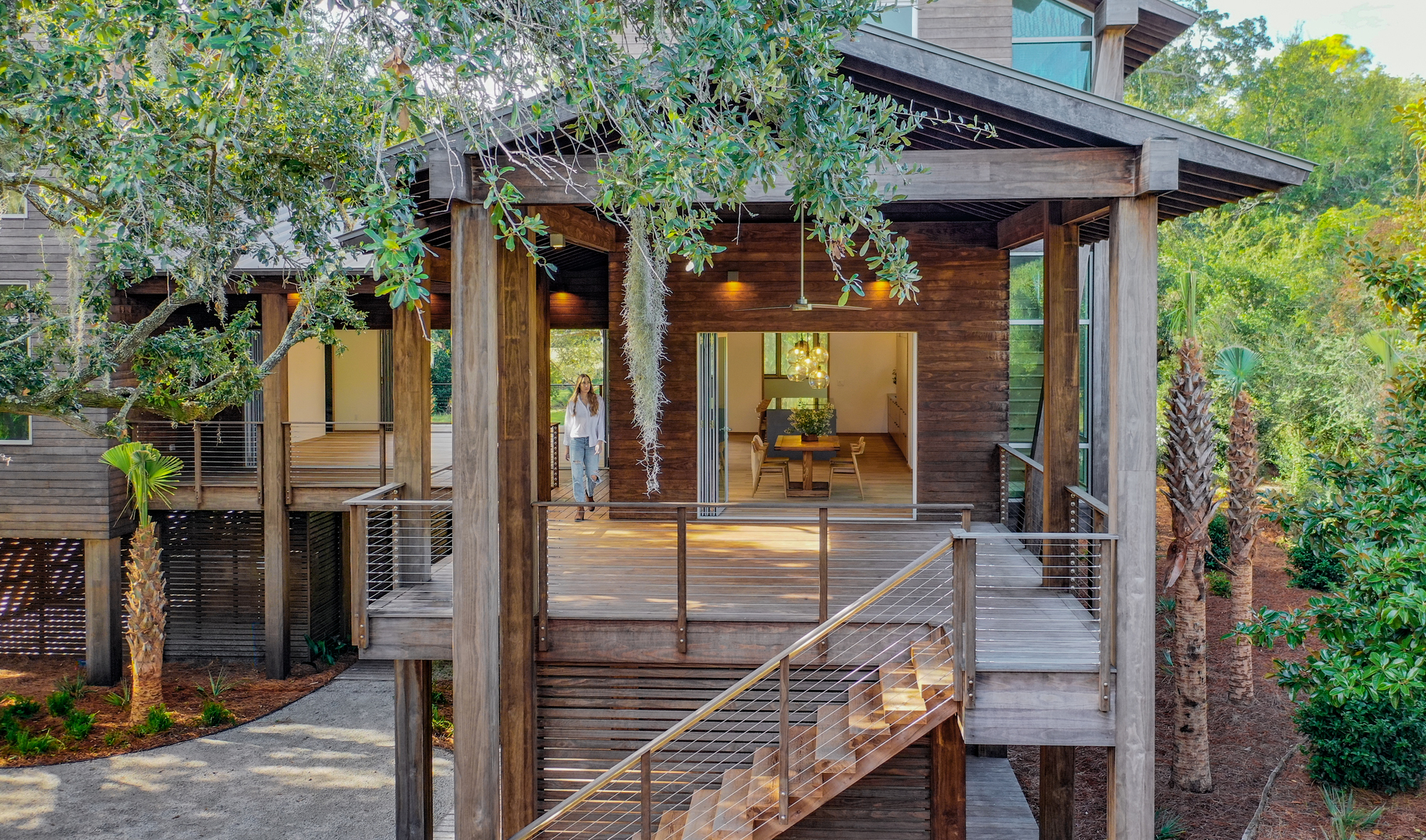 Elevated timber deck with open pavilion framed by heavy wood columns and cable railing at dusk