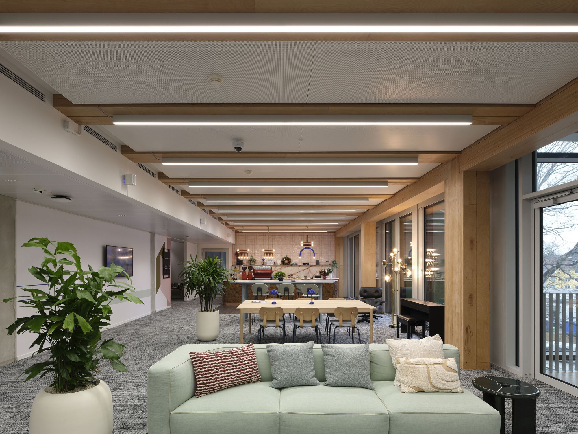 Common area with exposed timber beams and integrated lighting above seating and dining zones