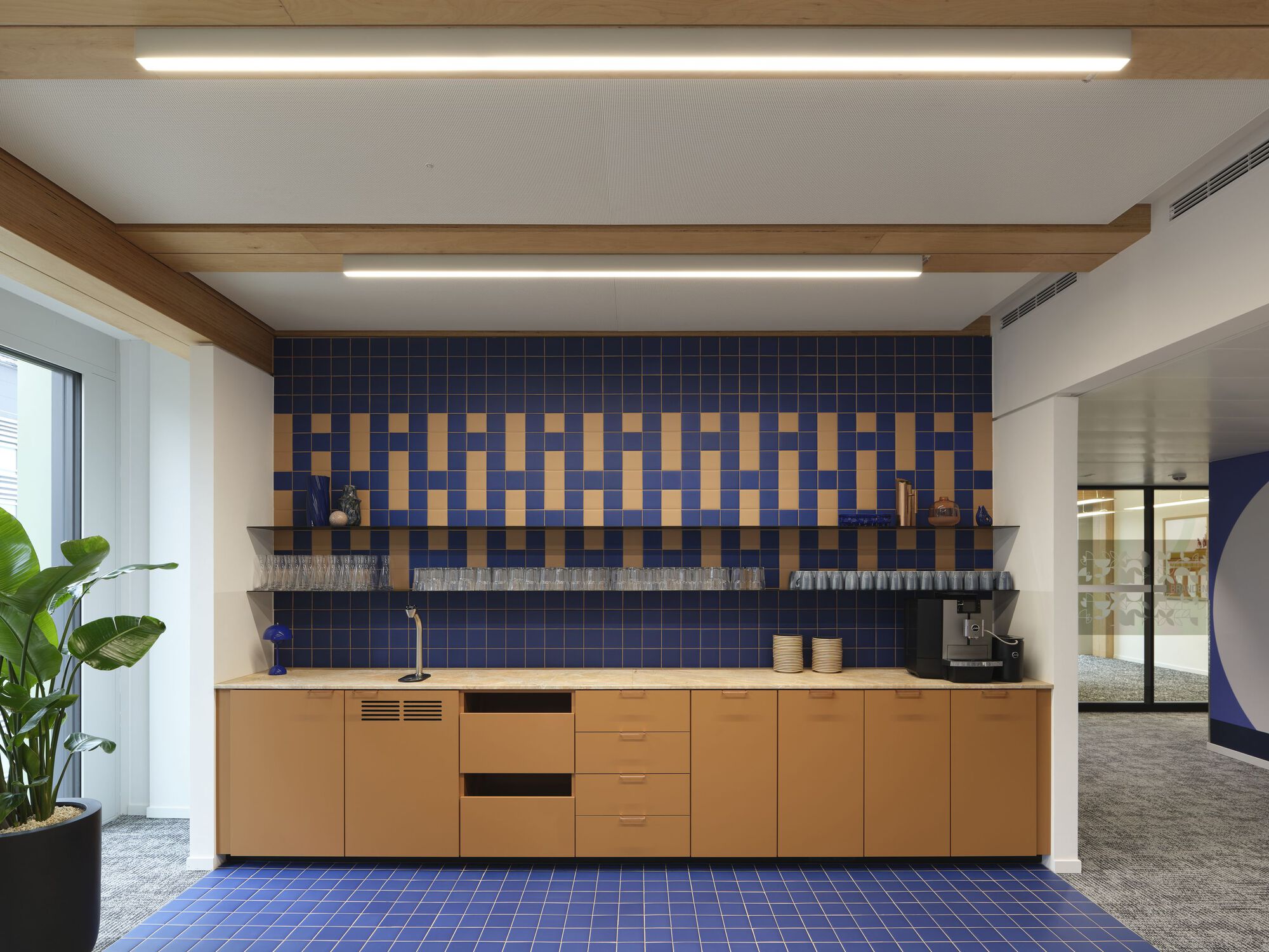 Kitchenette with blue and yellow patterned tile backsplash above timber cabinetry and open shelving