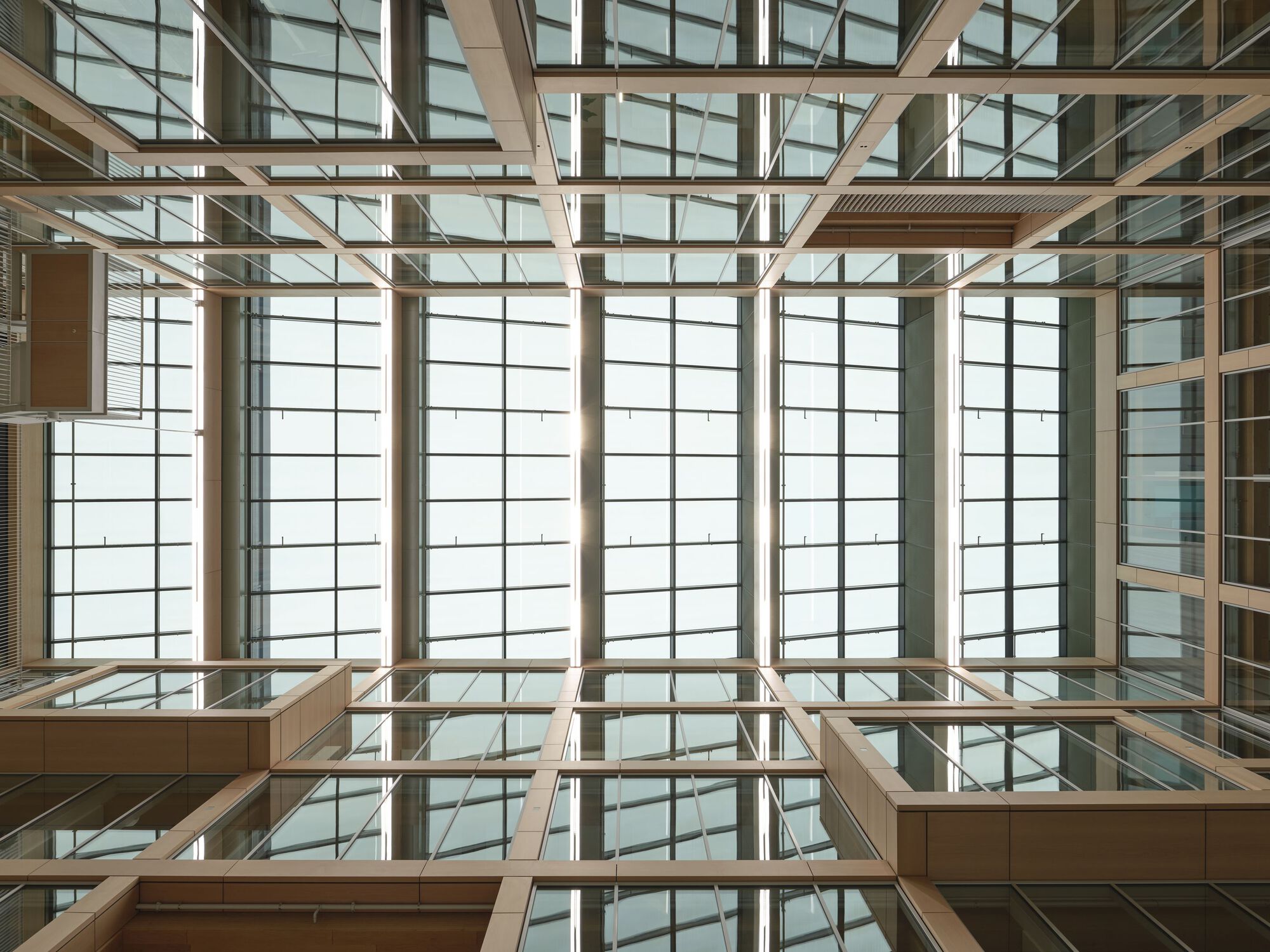 Upward view into a timber-framed atrium with gridded translucent panels flooding the space with diffused light