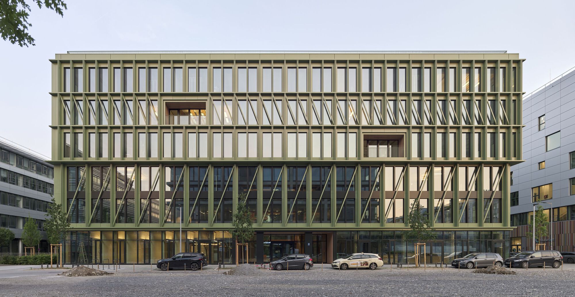 Street view of the layered facade with diagonal bracing and glass curtain wall under an overcast sky