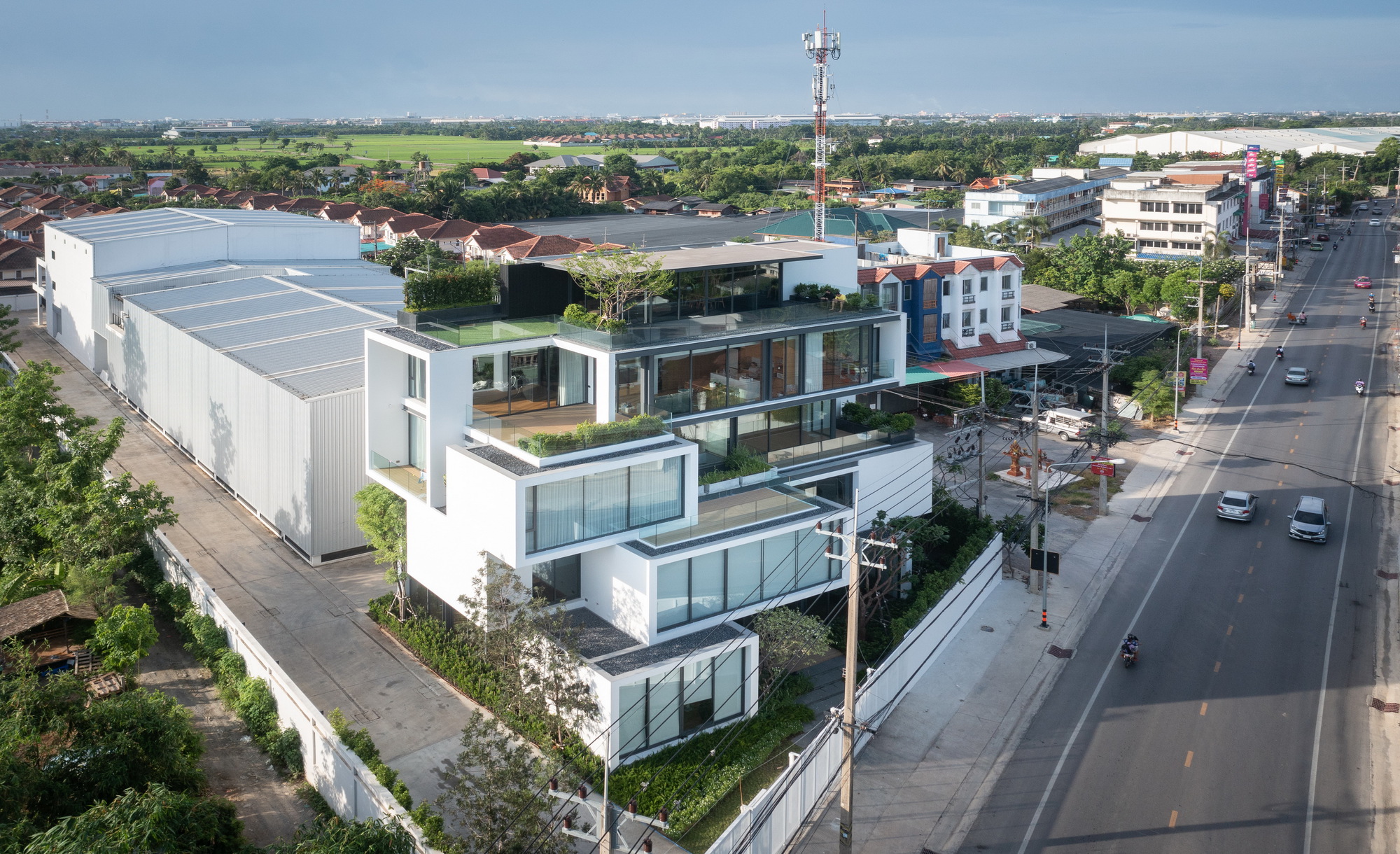 Aerial view of the terraced facade with offset volumes and rooftop gardens facing the roadway