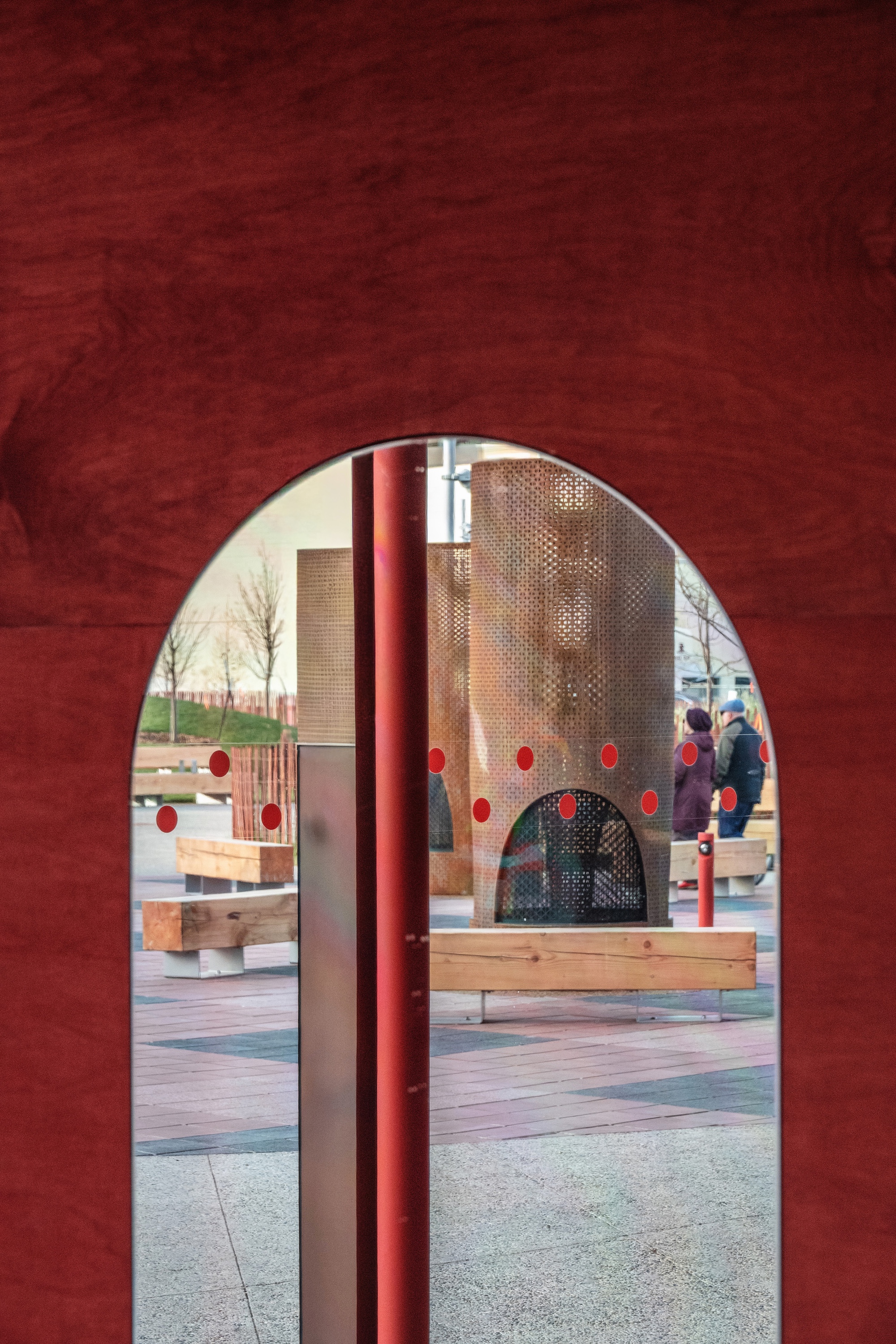 View through arched opening to outdoor play area with perforated brick screens and timber seating