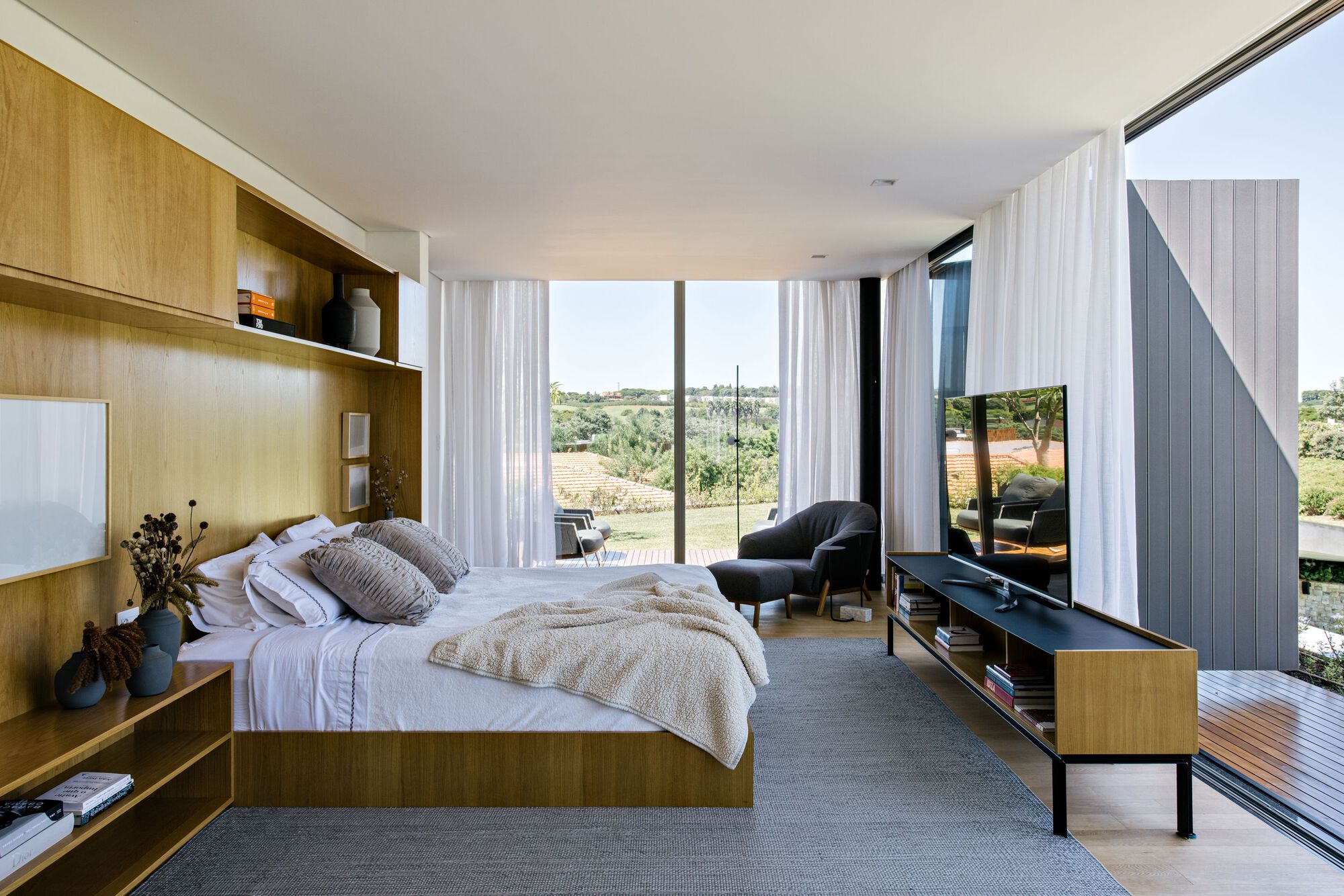 Bedroom with integrated timber joinery and floor-to-ceiling glazing overlooking the landscape