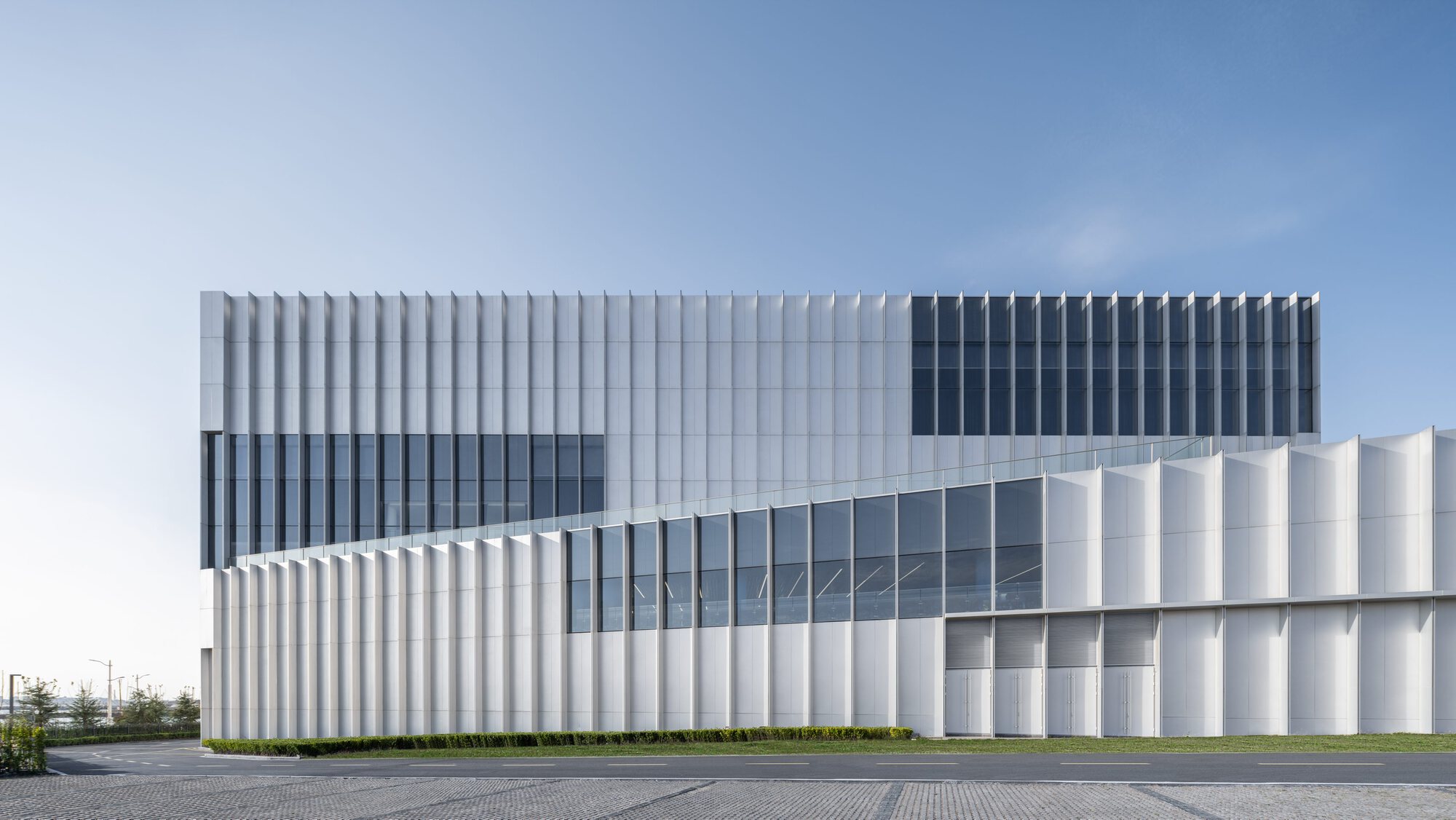 Side elevation showing the vertically ribbed metal cladding and horizontal glazed band under clear sky