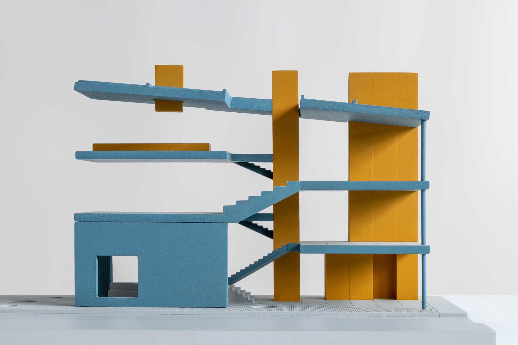 Sectional model revealing interconnected floor plates with diagonal staircases threading through yellow cores