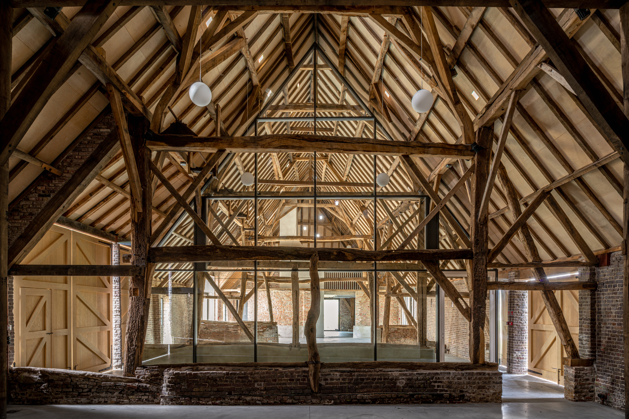 Exposed timber roof structure with diagonal bracing and pendant lights illuminating the central volume