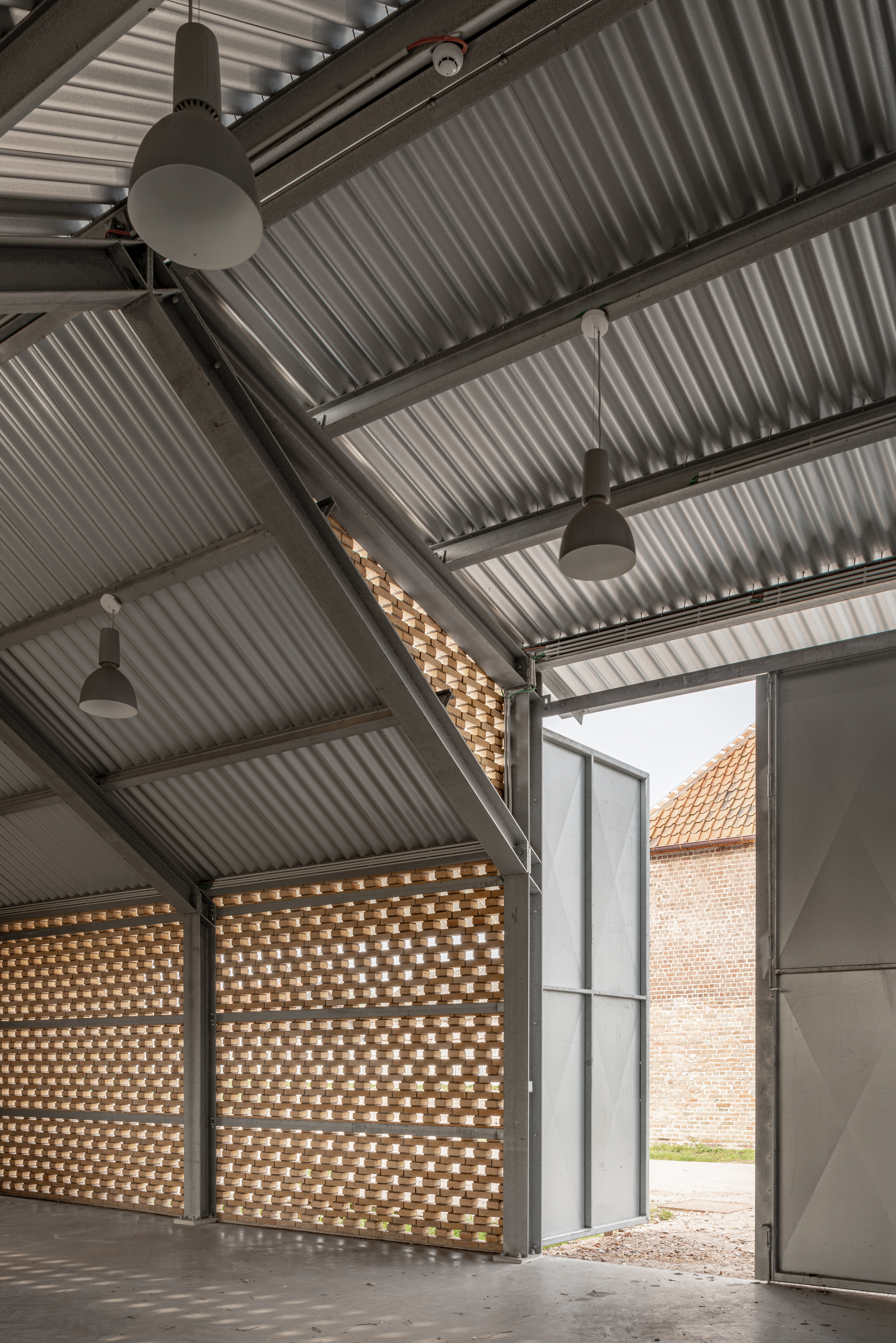 Large doors opening from interior space to courtyard framed by perforated brick screens