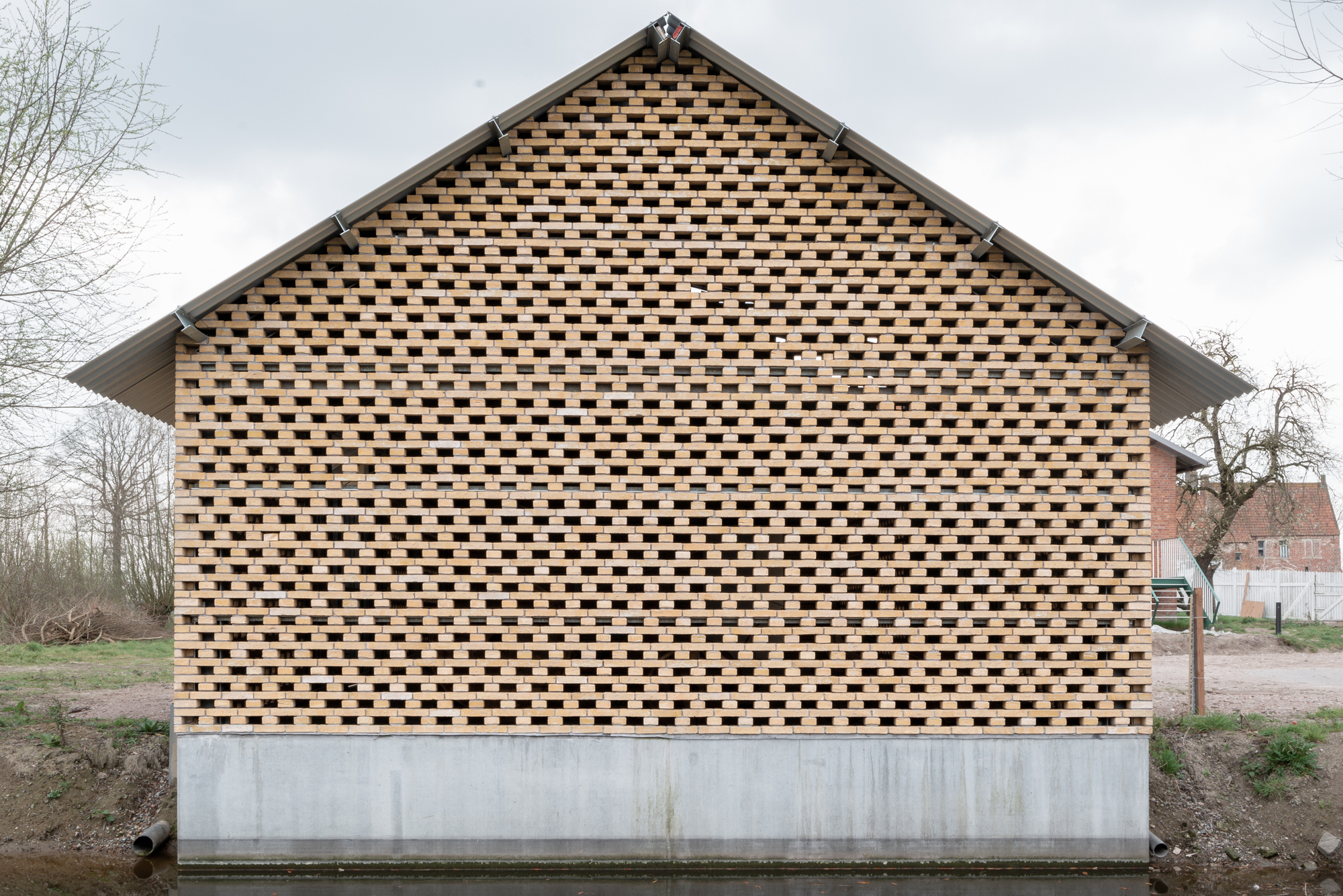Gable end with chequered brick pattern atop a concrete plinth under an overcast sky