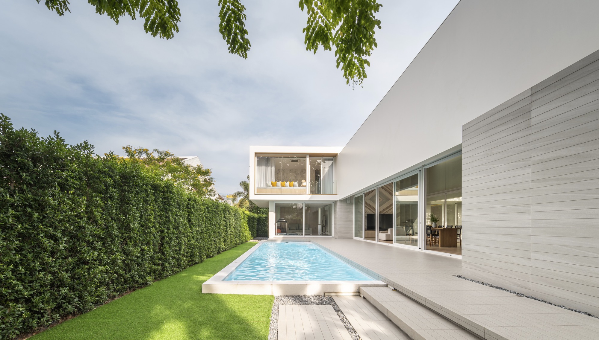 Rear courtyard with rectangular pool bordered by lawn and floor-to-ceiling glazing