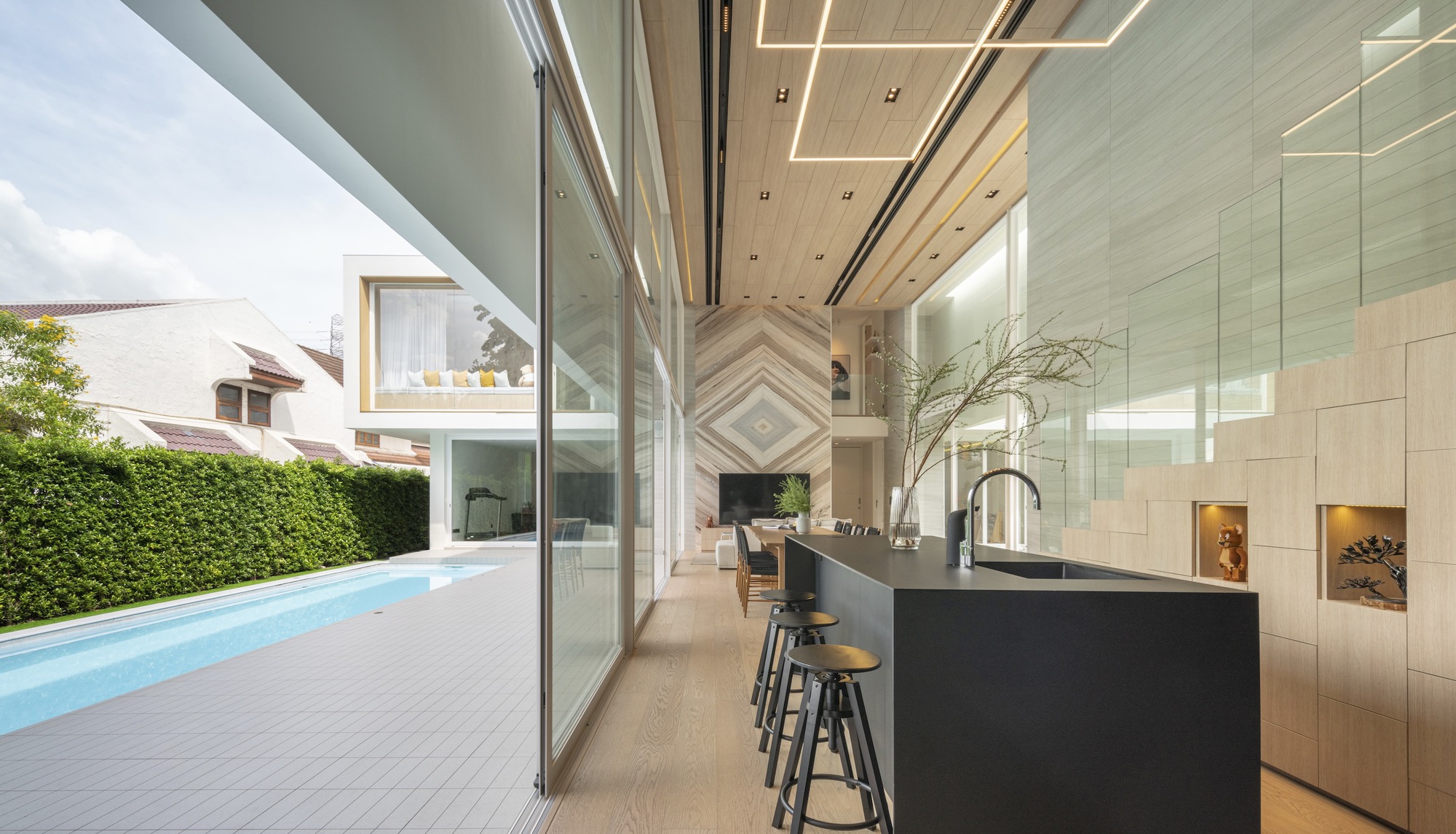 Kitchen island and sliding glass doors opening to pool terrace with trimmed hedge backdrop