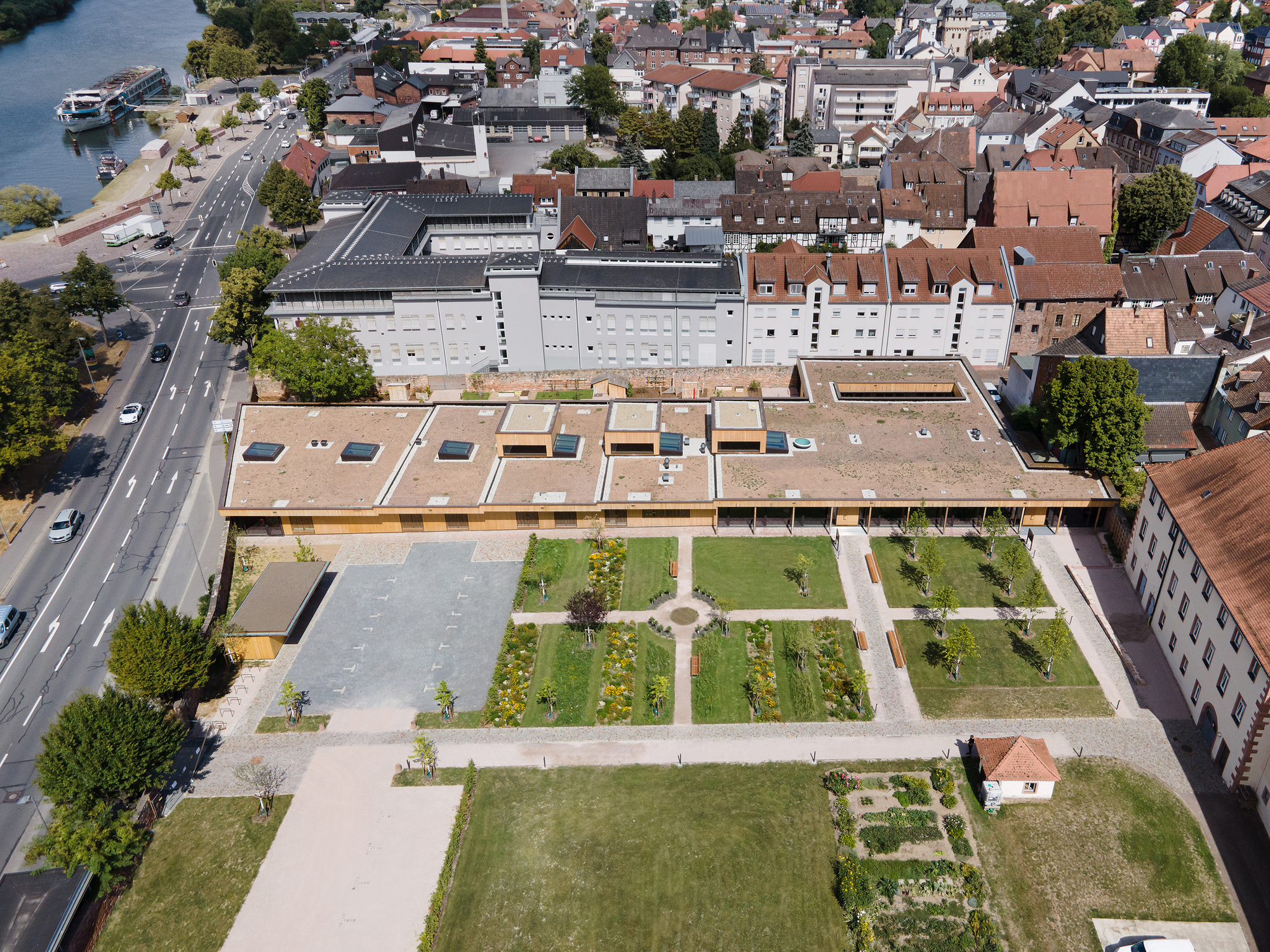 Aerial view of flat timber roof with skylights overlooking geometric courtyard garden and surrounding town