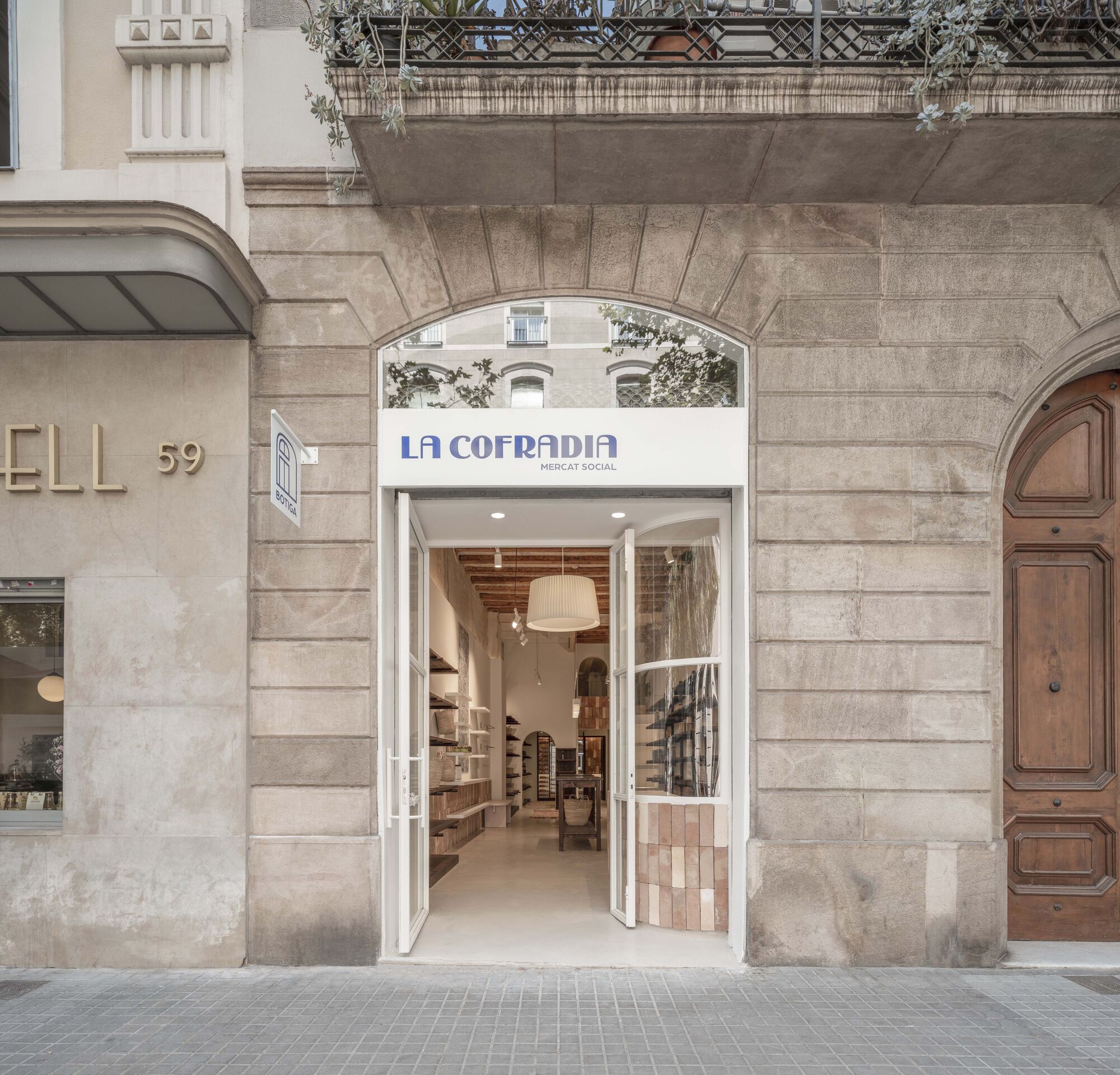 Street facade with arched stone entry and white-framed glass doors opening to the shop interior