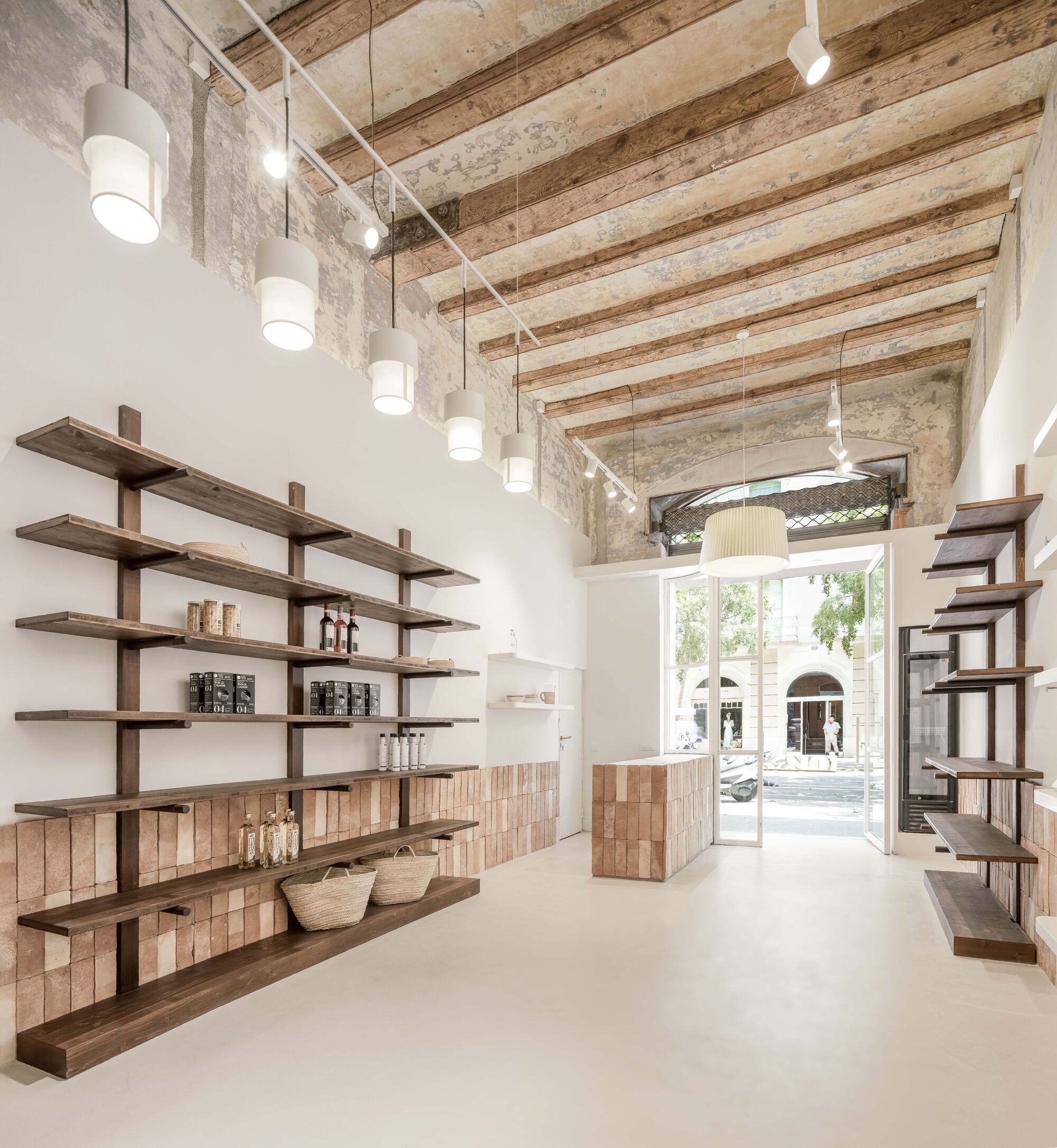 Interior retail space with exposed timber ceiling beams and pendant lights overlooking arched storefront