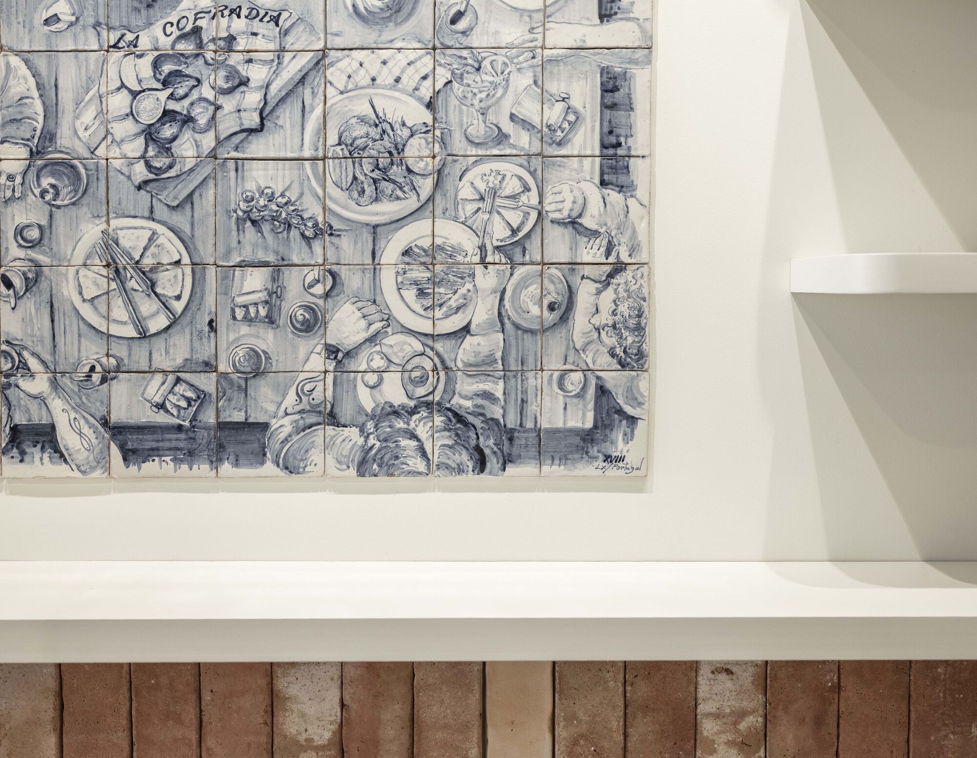 Blue and white ceramic tile mural depicting plates and tableware above stone tile counter