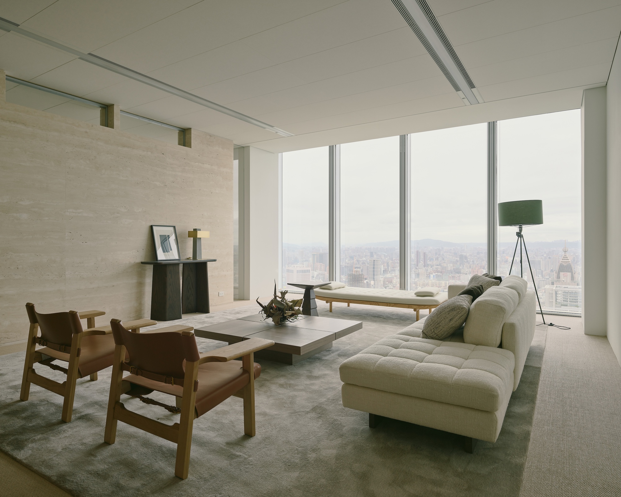 Corner room with floor-to-ceiling glazing overlooking the city skyline on an overcast day