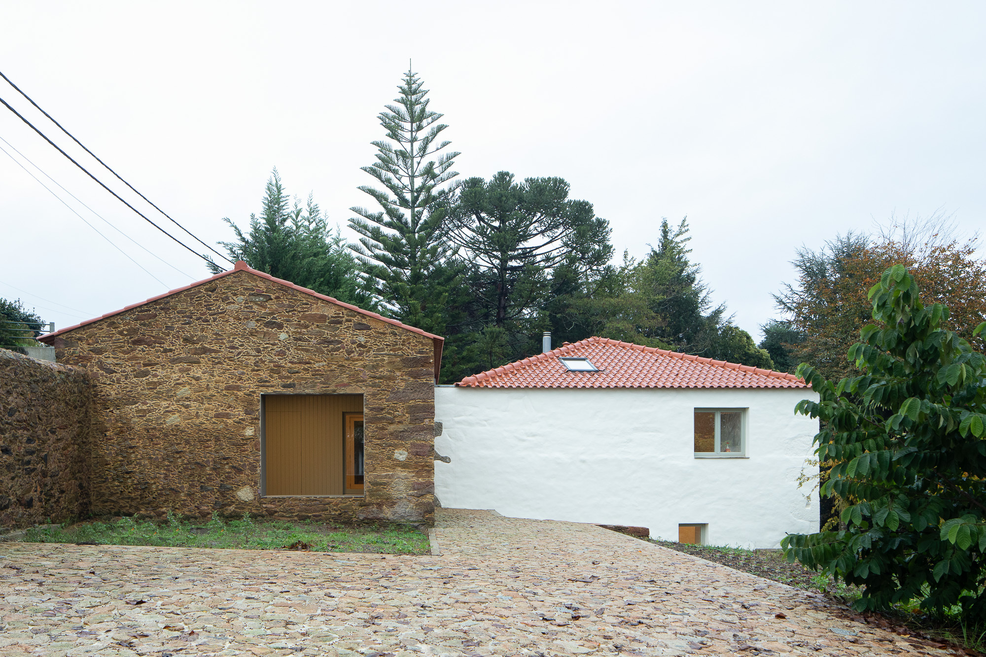 Courtyard view showing stone barn, white rendered house with tile roof, and cobblestone forecourt