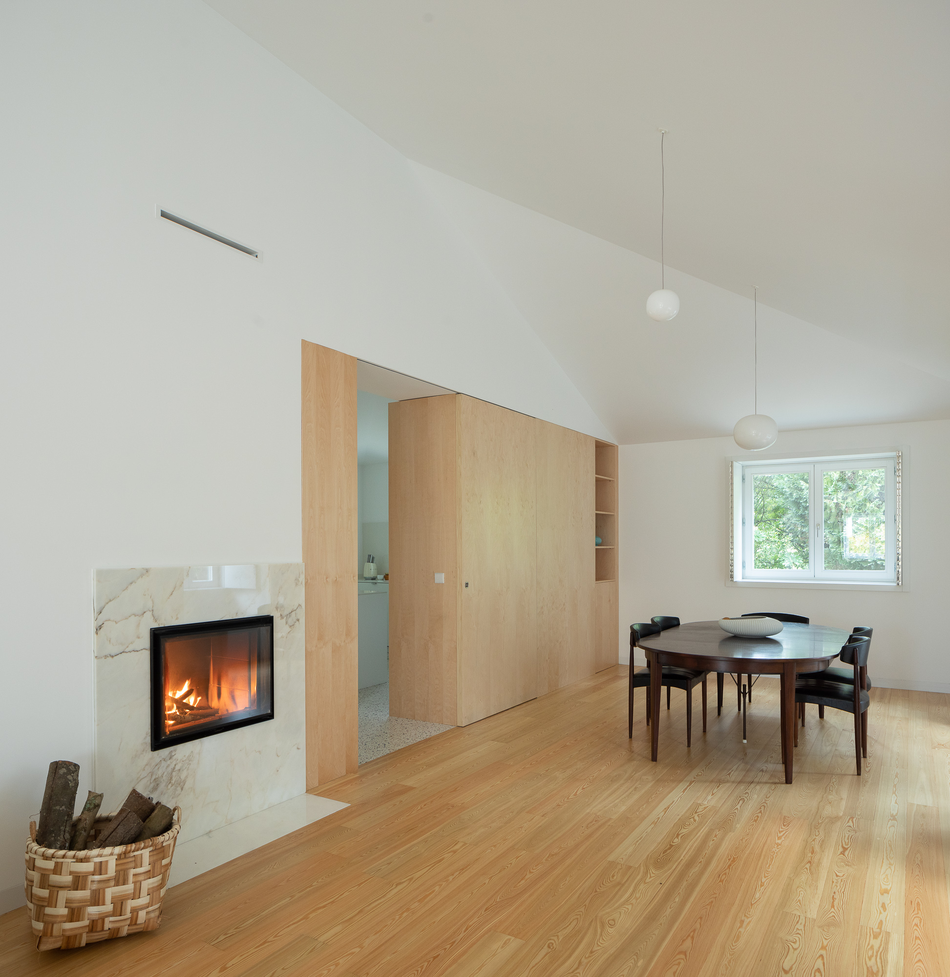 Living room with marble fireplace surround, sliding wood partition and pendant lights under a vaulted ceiling