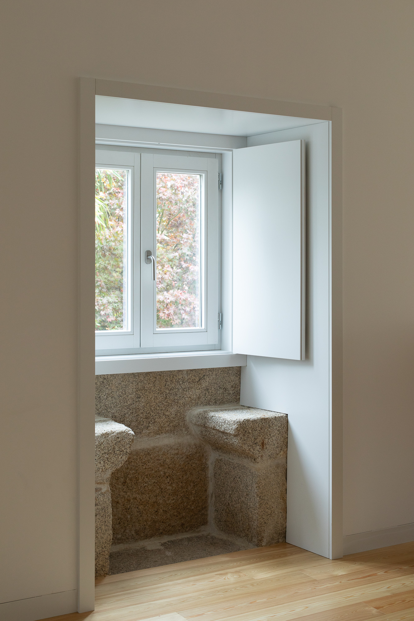 Terrazzo-lined window seat alcove with casement window opening to garden greenery