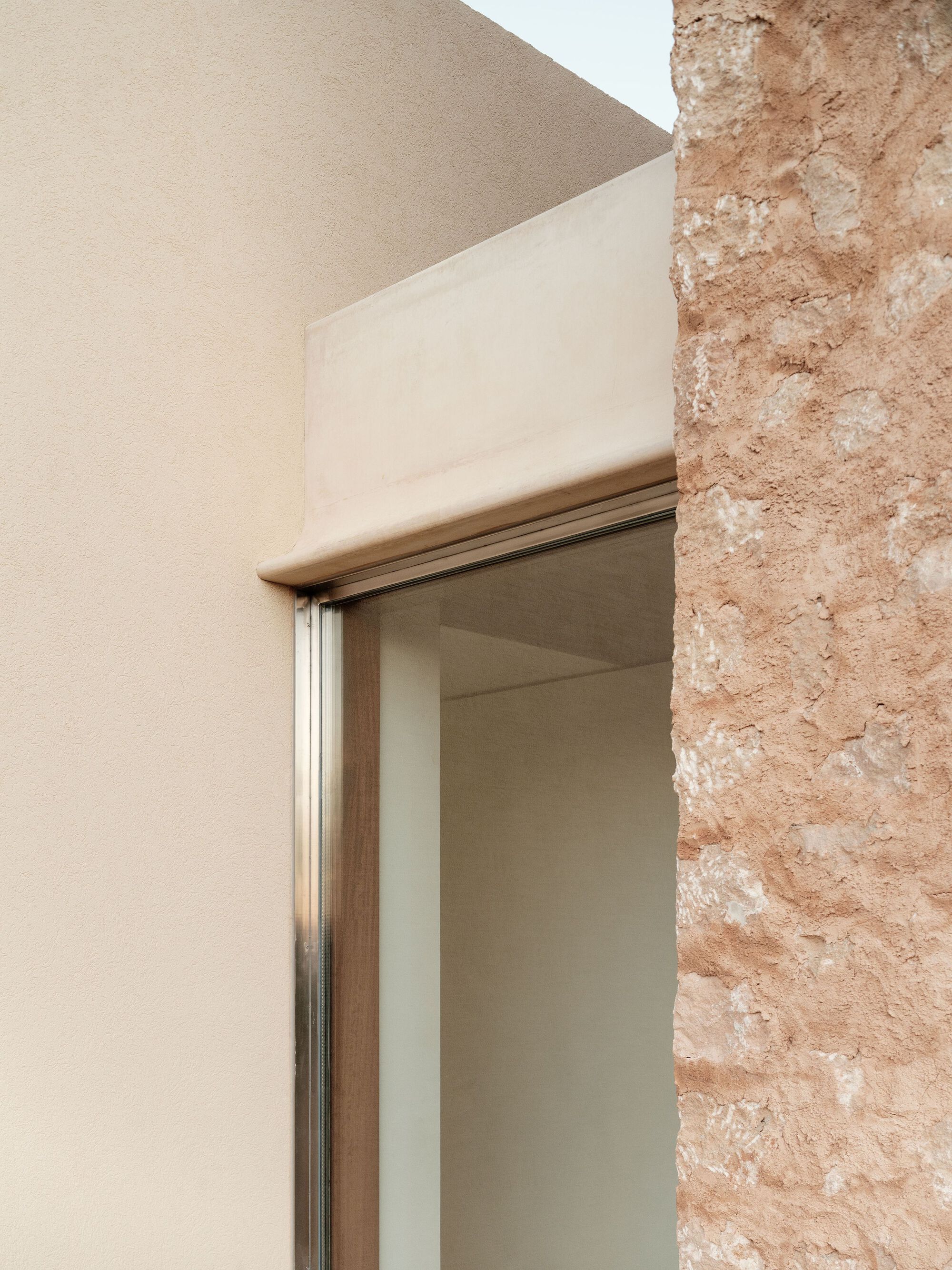 Detail of timber doorframe meeting the rough textured stone wall and smooth plaster corner